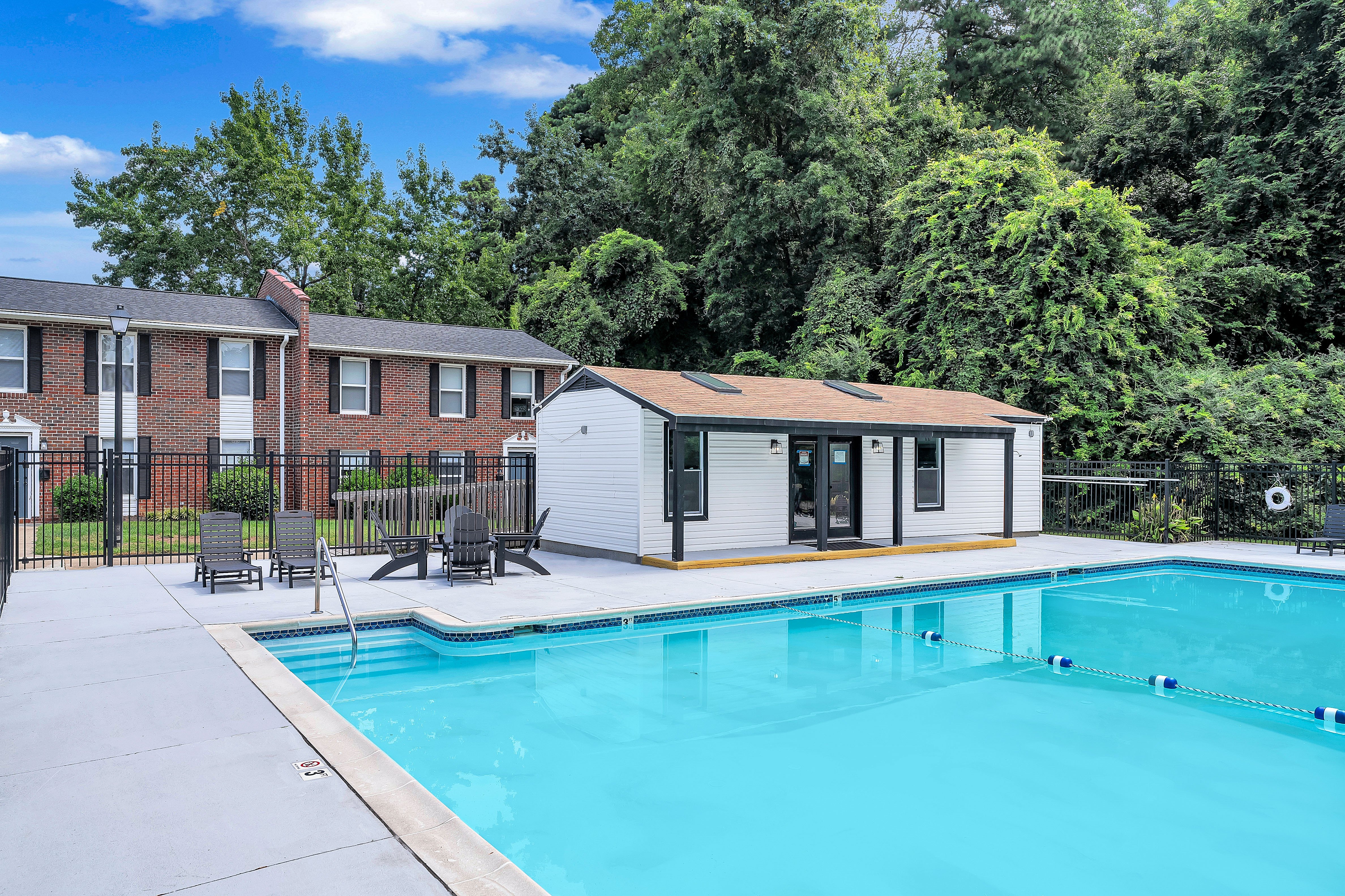 A swimming pool in front of a house with a white exterior.