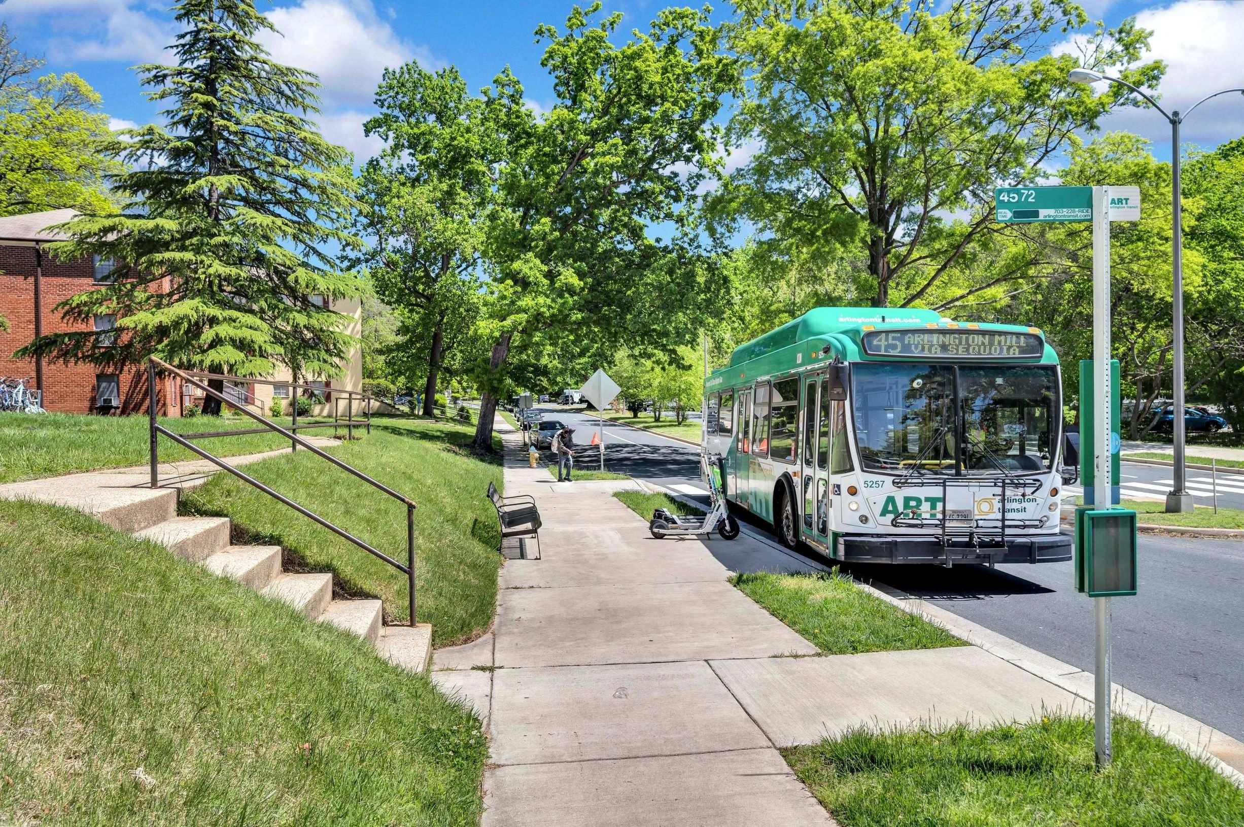 A green bus with the word ART on the front is driving down a street.