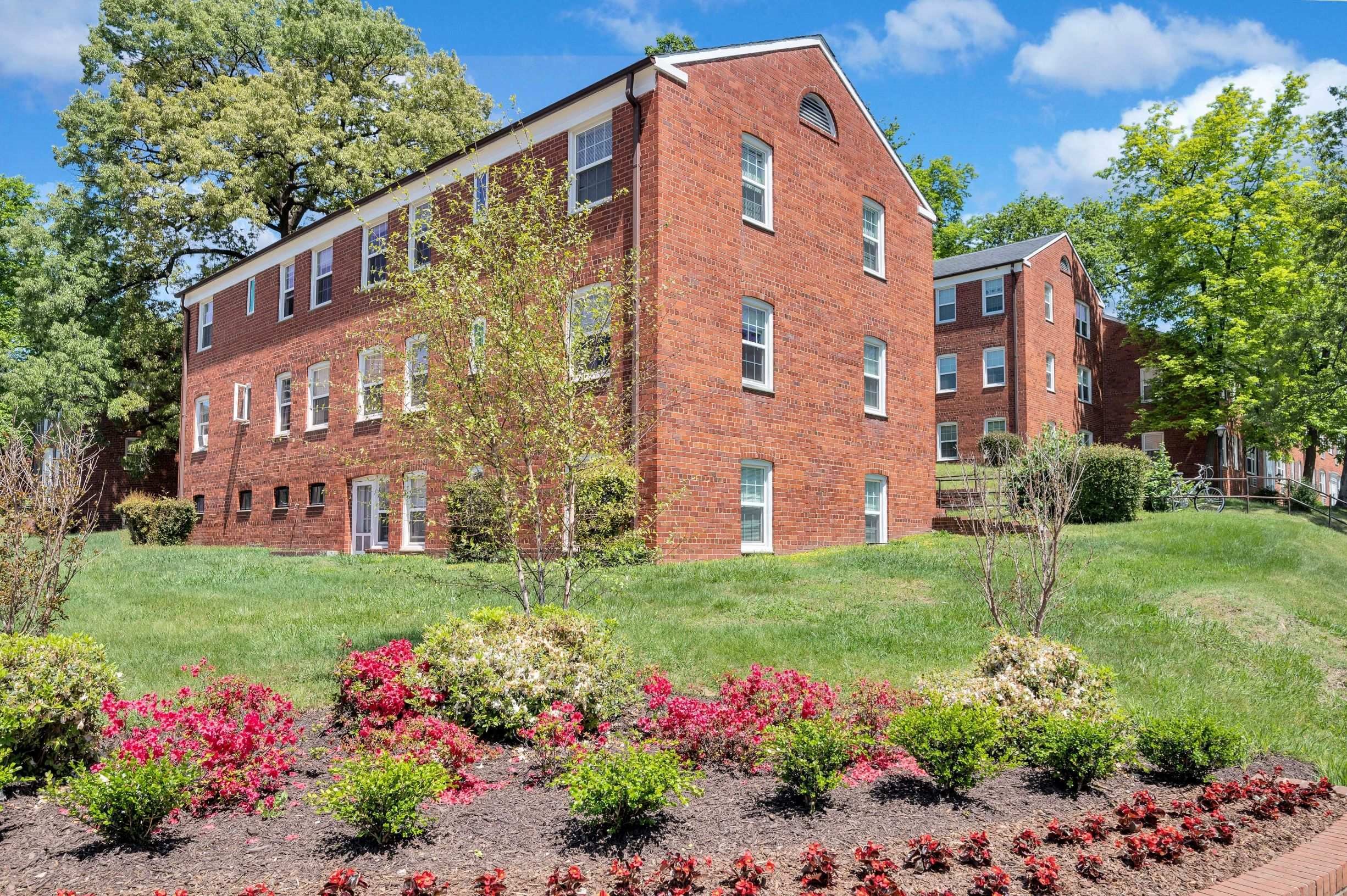 A red brick building with a garden in front.