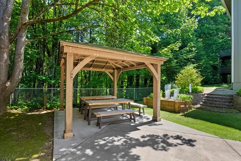 a picnic table under a wooden pavilion in a backyard