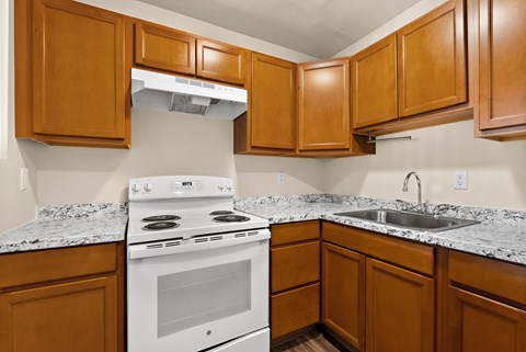a kitchen with white appliances and granite counter tops and wooden cabinets