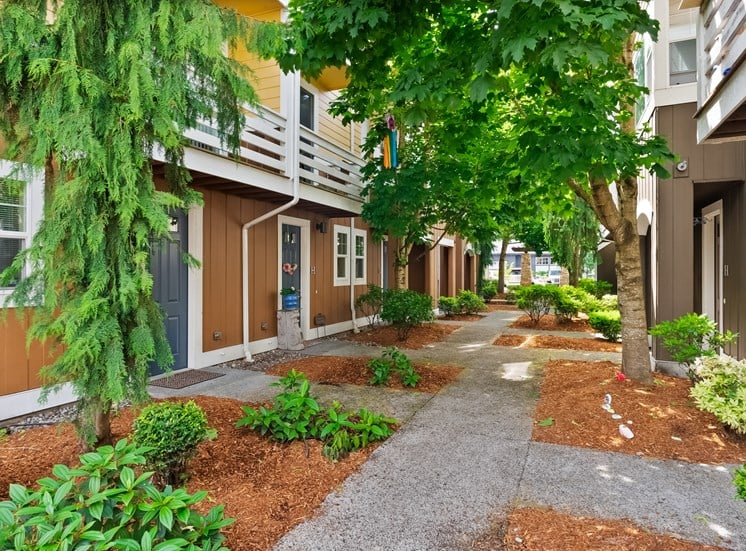 a walkway between two apartment buildings with trees and plants