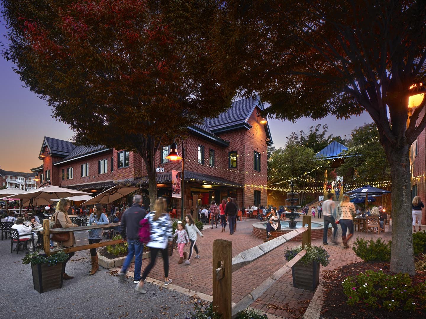 People walking around the shops at Eagleview Town Center near a water fountain.