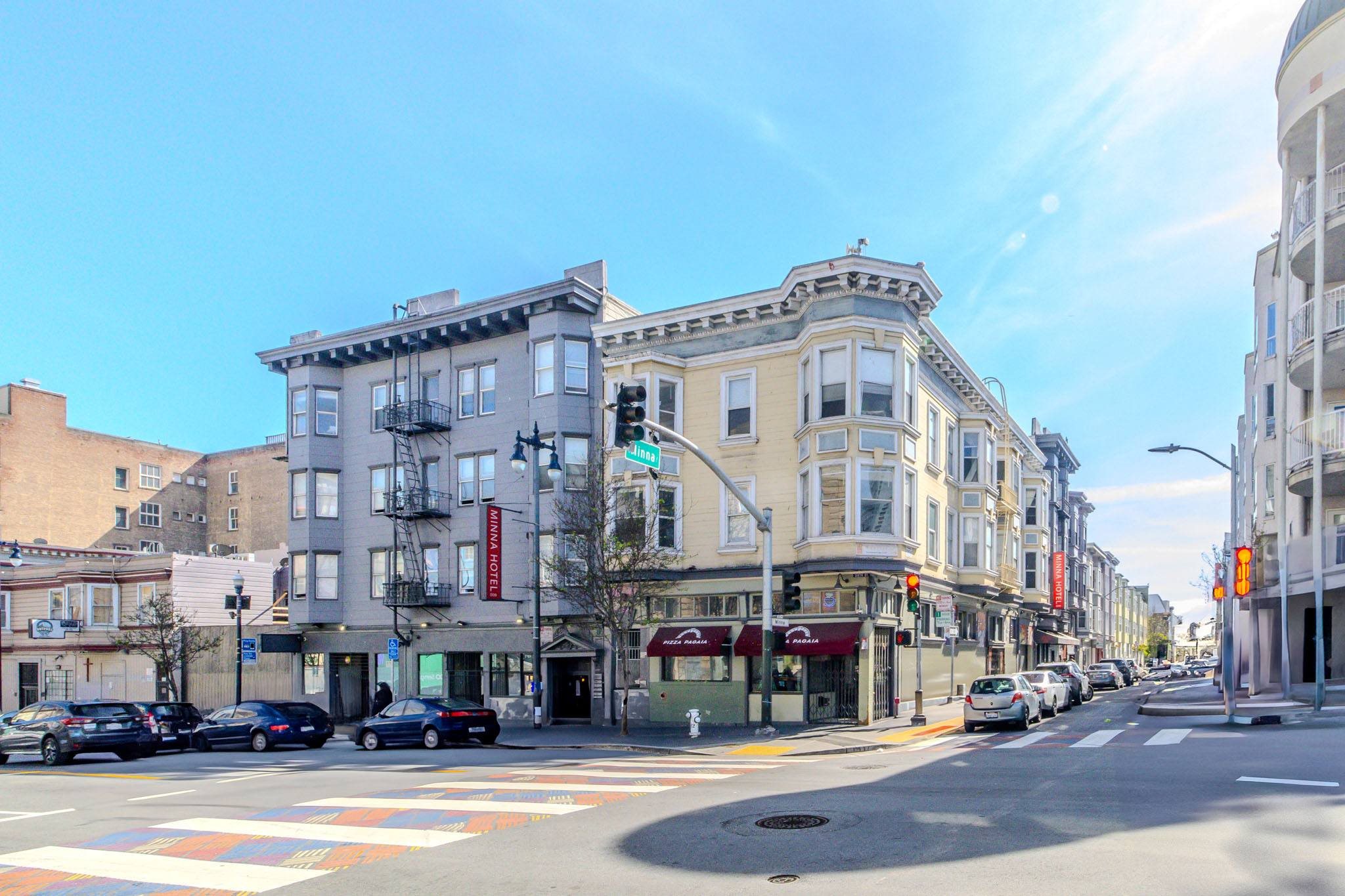 A street view of a city with buildings on both sides and cars parked on the side of the road.