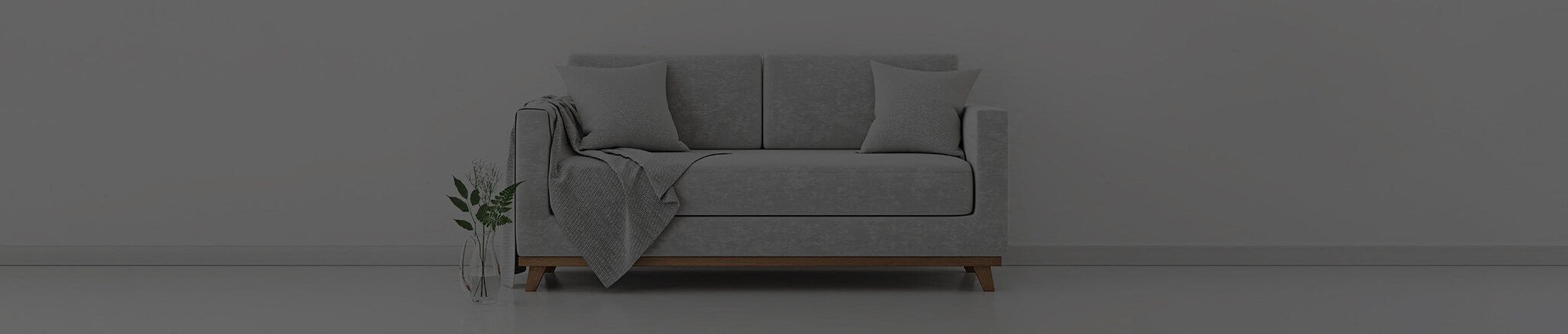 Gray couch with a white background and a vase