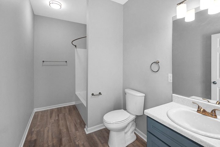 A white toilet sits in a bathroom next to a sink.