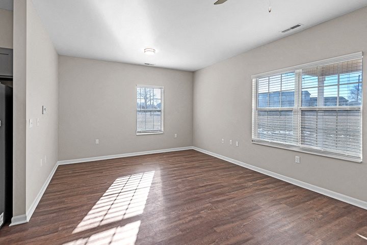 A room with wooden floors and a window with blinds.
