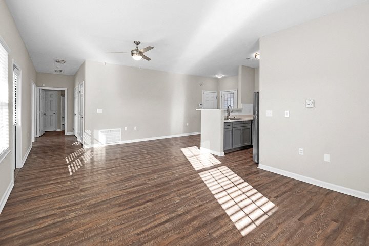 A spacious room with wooden flooring and a ceiling fan.