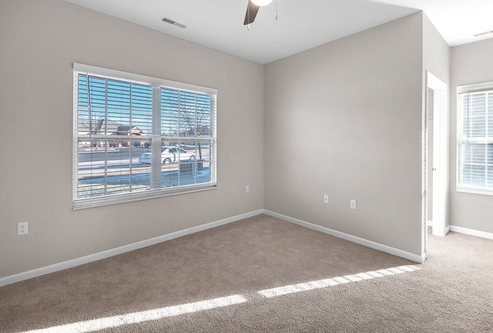 A room with a large window and a carpeted floor.