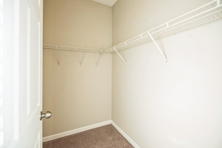A white closet with a white door and a white shelf.