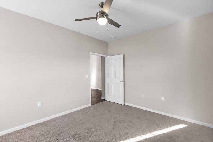 A room with a ceiling fan and a door.