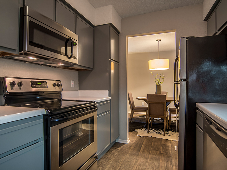 Our Kitchen with a built-in microwave. Dark wood flooring, stainless steel appliances, light countertops, dark cabinets.