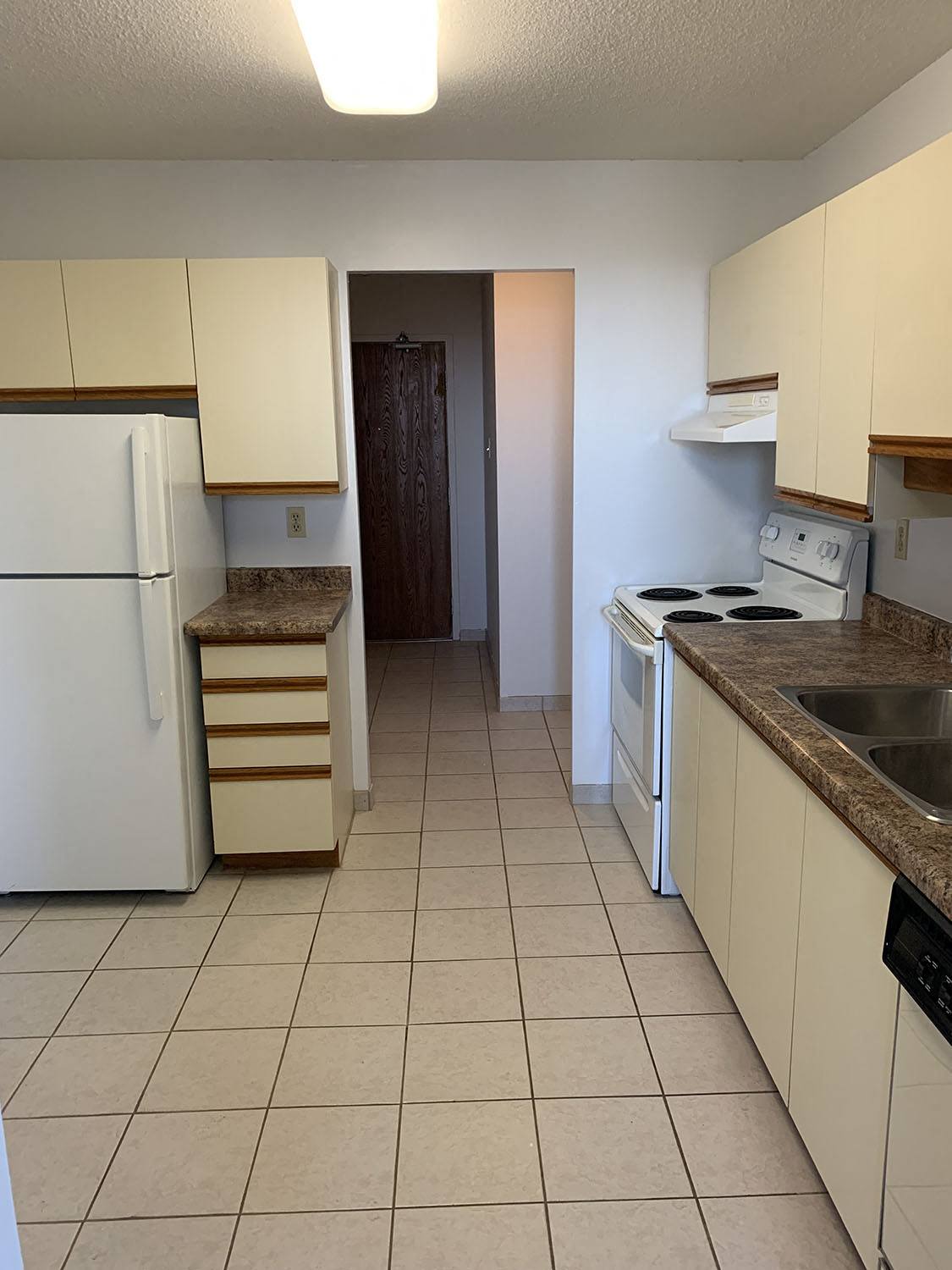 a kitchen with white cabinets and a refrigerator and a sink