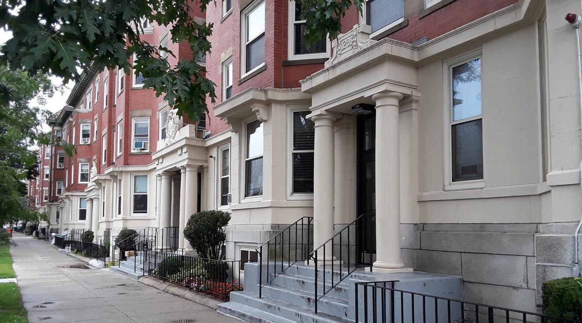 Brick and stucco apartment buildings on a tree lined street