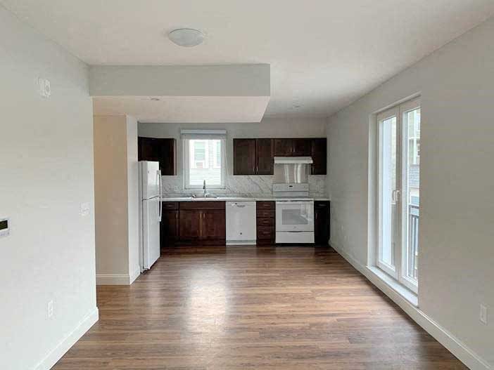 Modern plank flooring, large bright windows, open floor plan.