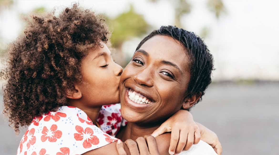 Happy family, child kisses smiling mother.