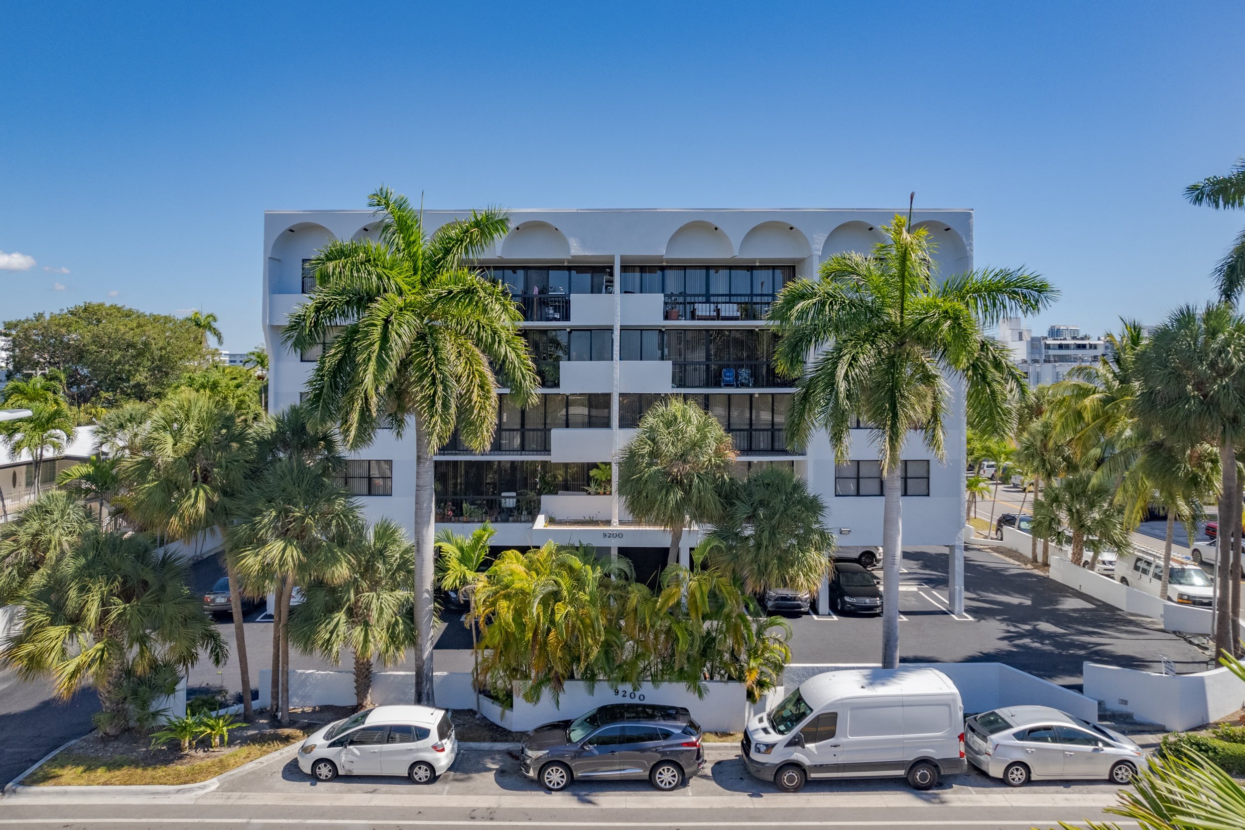 a building with palm trees and cars parked in front of it