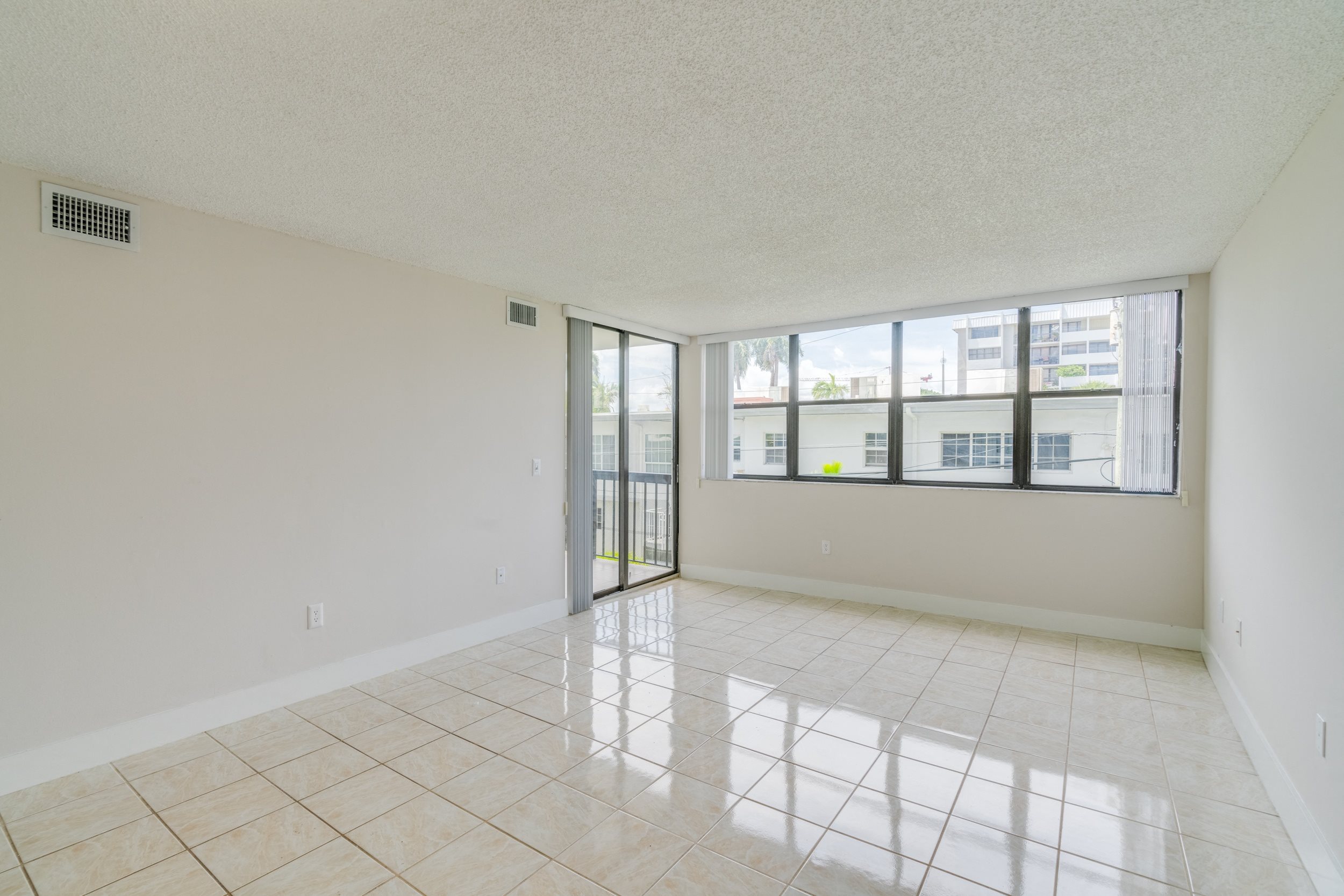 an empty living room with a large window and a tiled floor