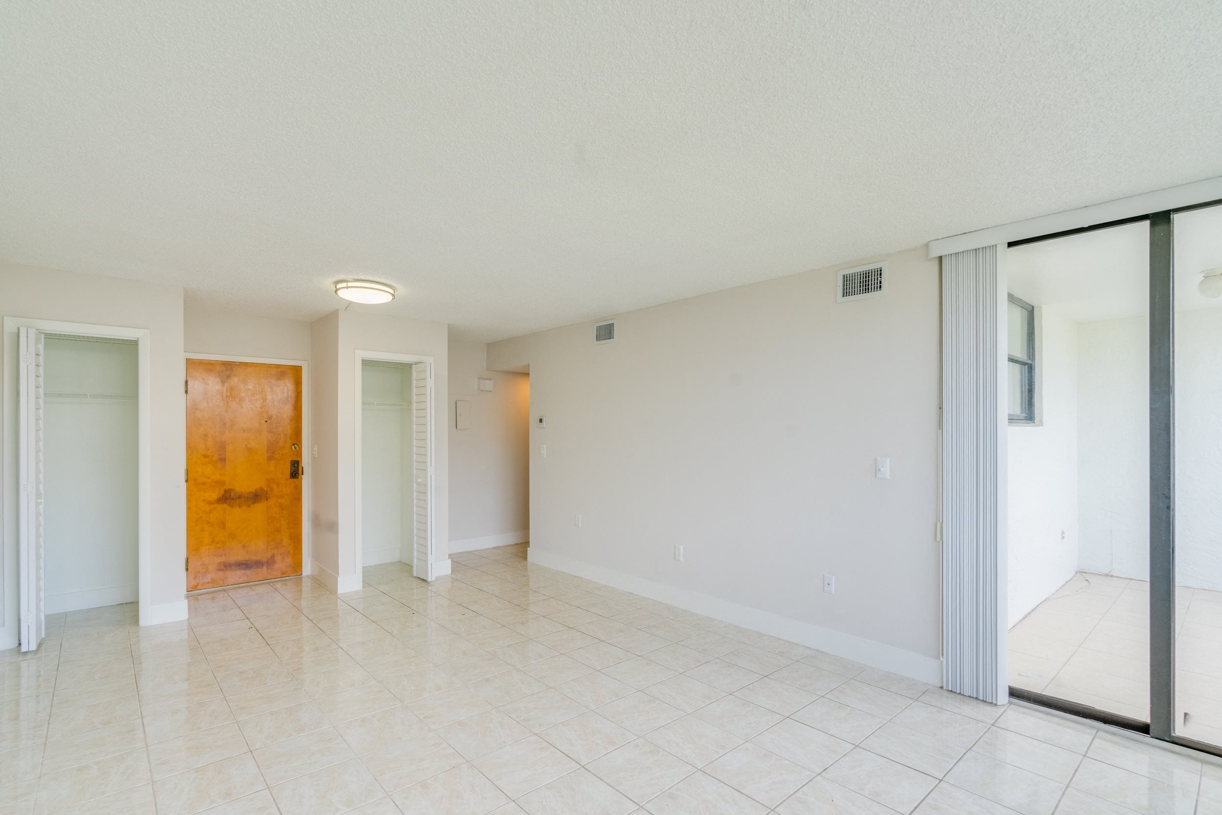 an empty living room with sliding glass doors and a tiled floor