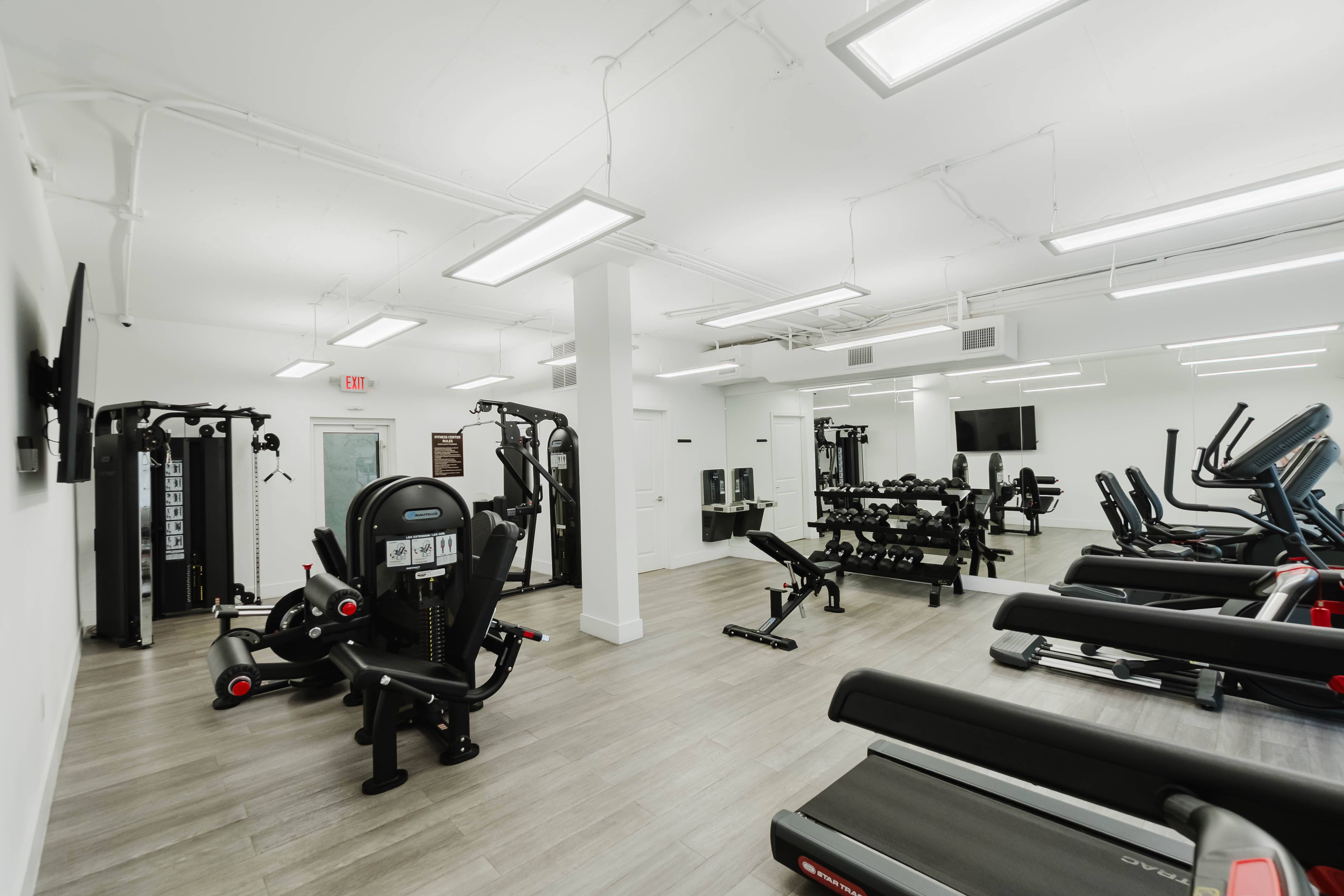 A gym with treadmills, weights, and exercise equipment.