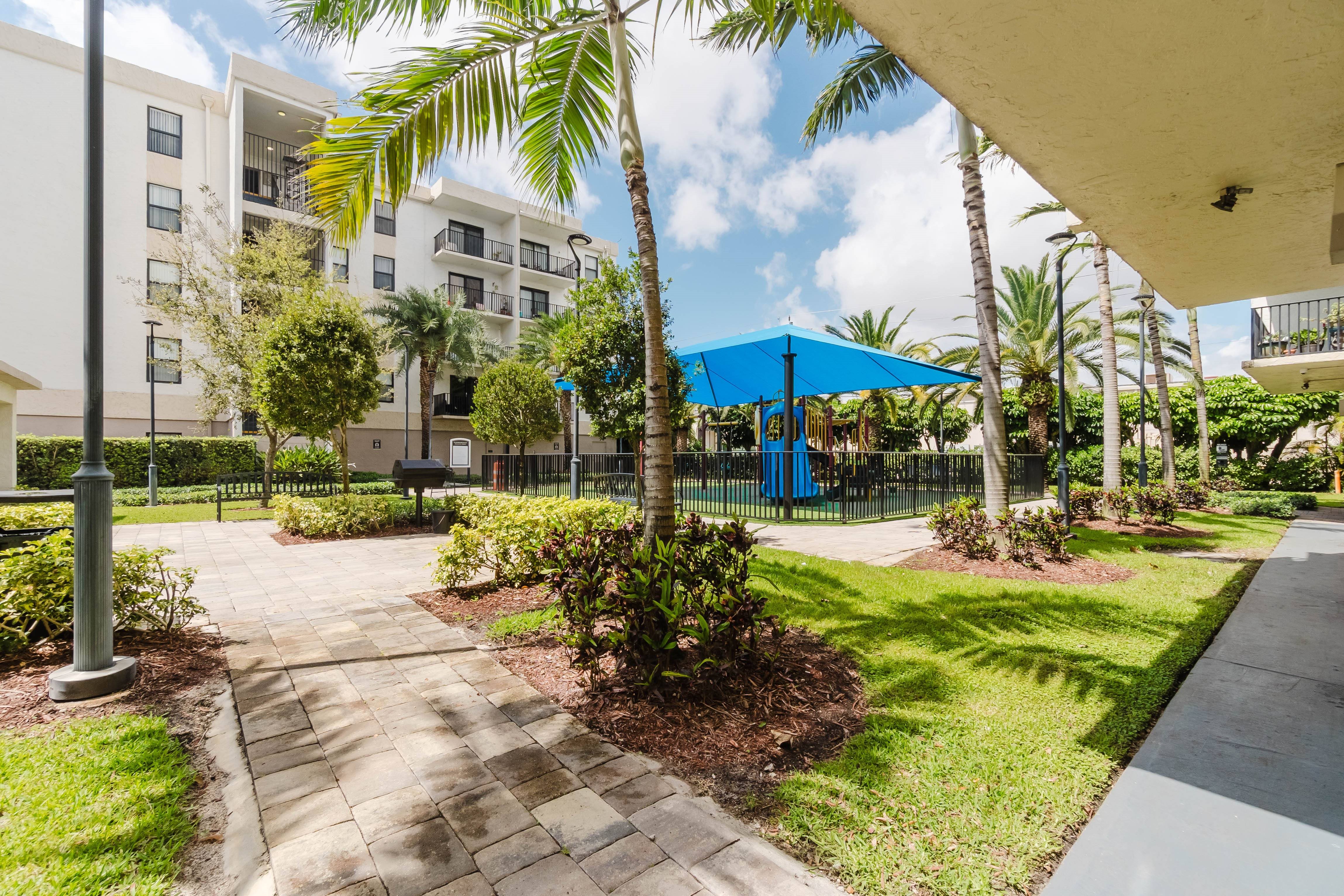 A sunny day at a residential area with a blue umbrella and palm trees.