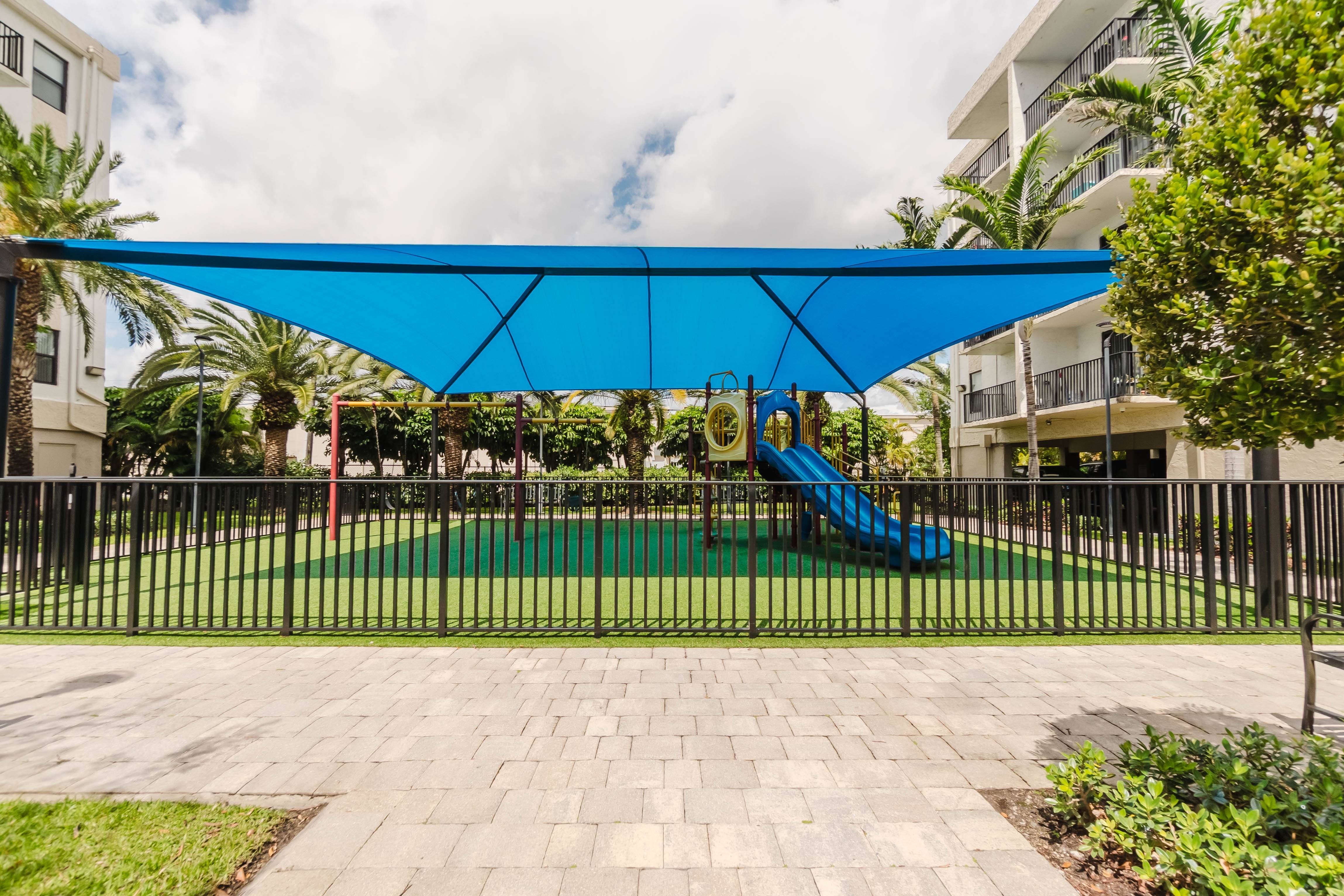 A playground with a blue slide and a blue shade structure.