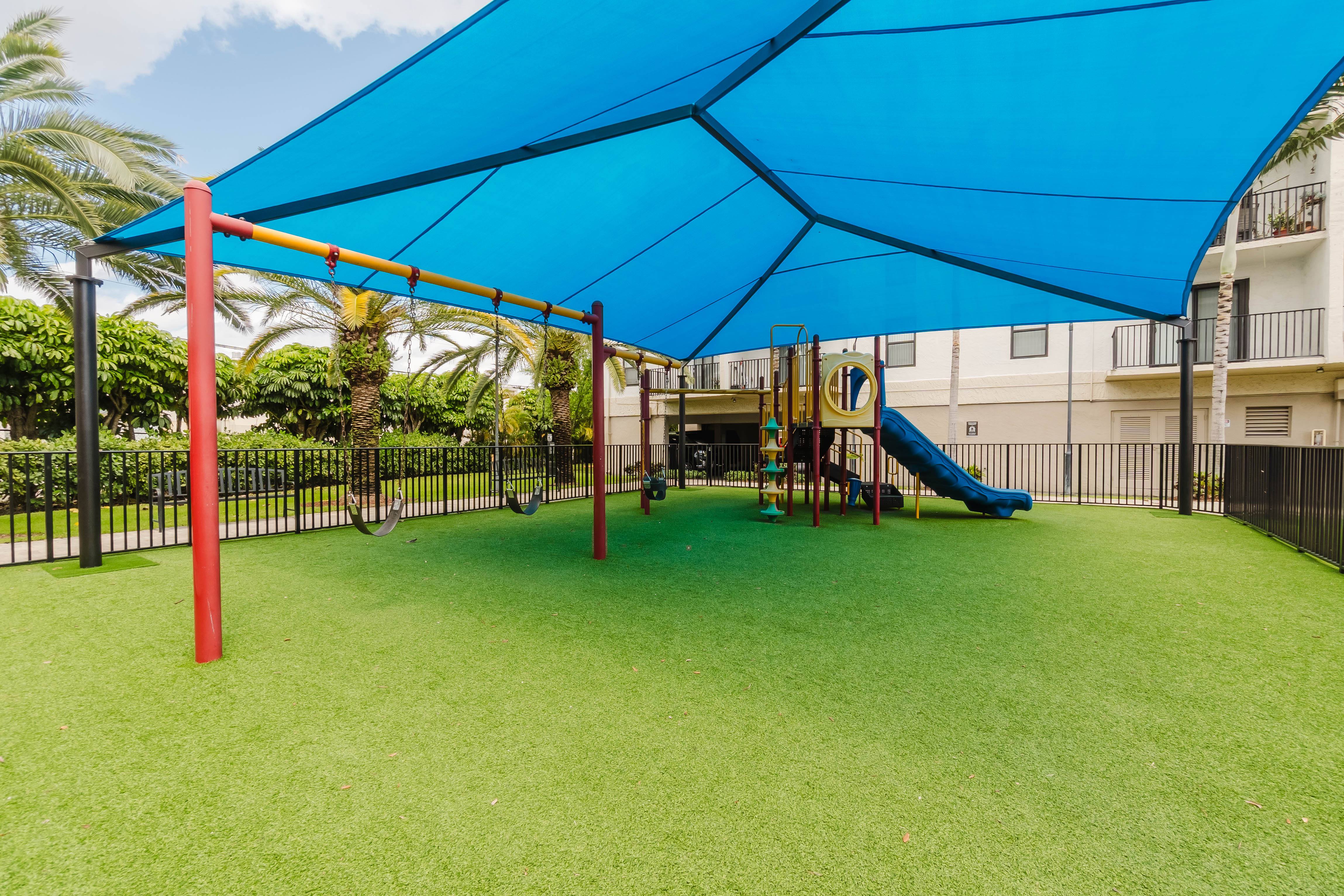 A playground with a blue canopy and a yellow slide.