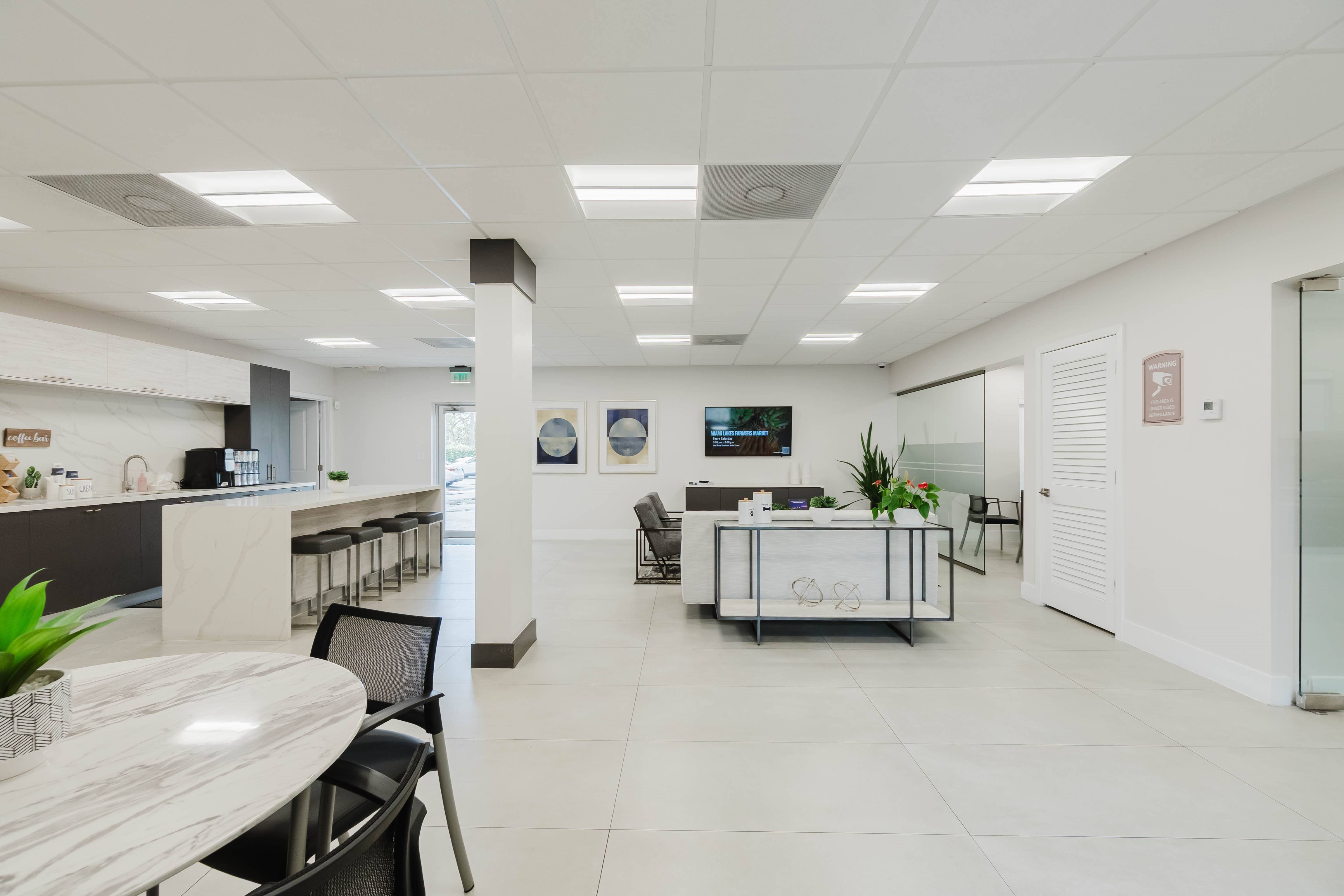 A modern office space with a white color scheme and a variety of furniture.