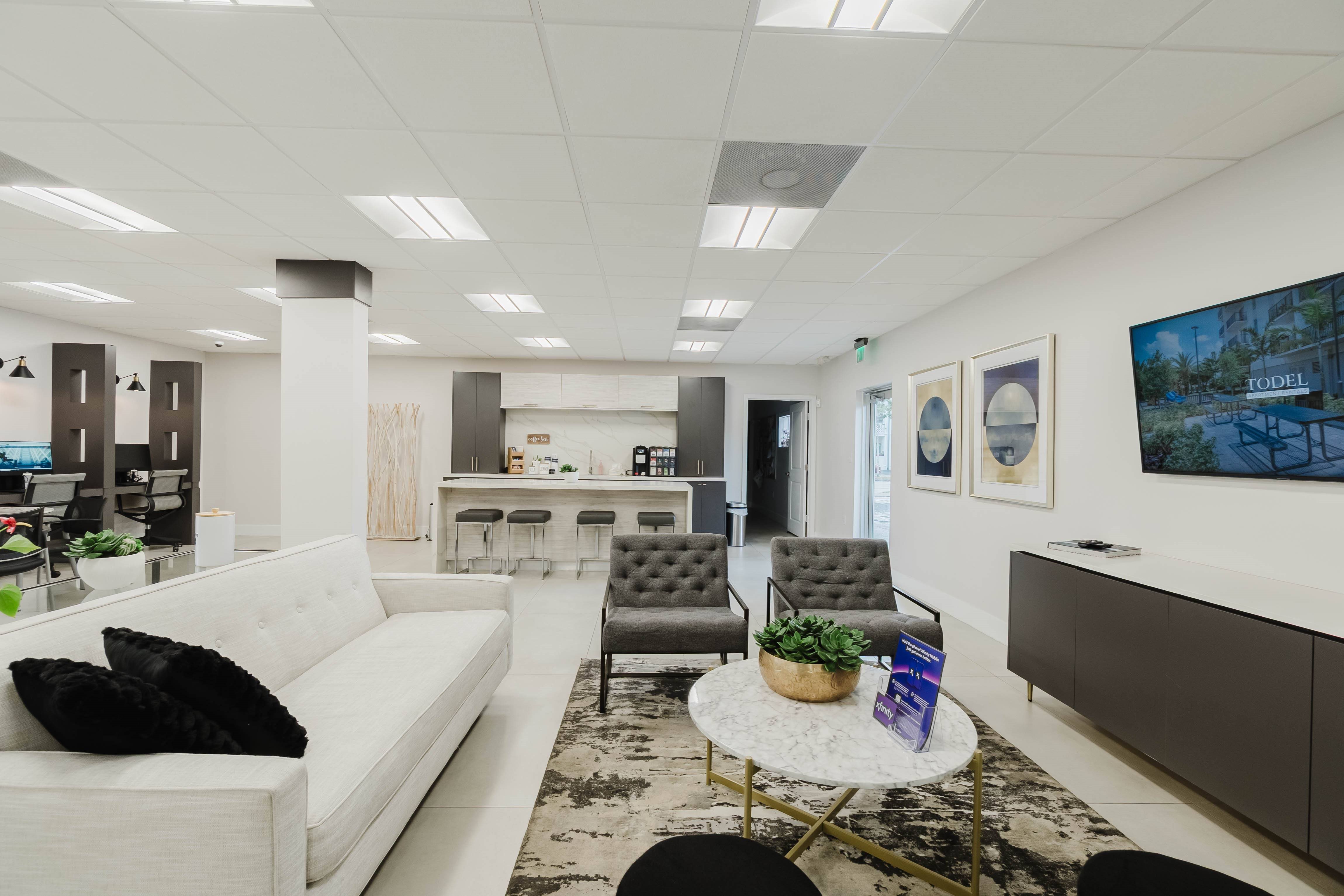 A modern office space with a white sofa, a grey armchair, and a coffee table.