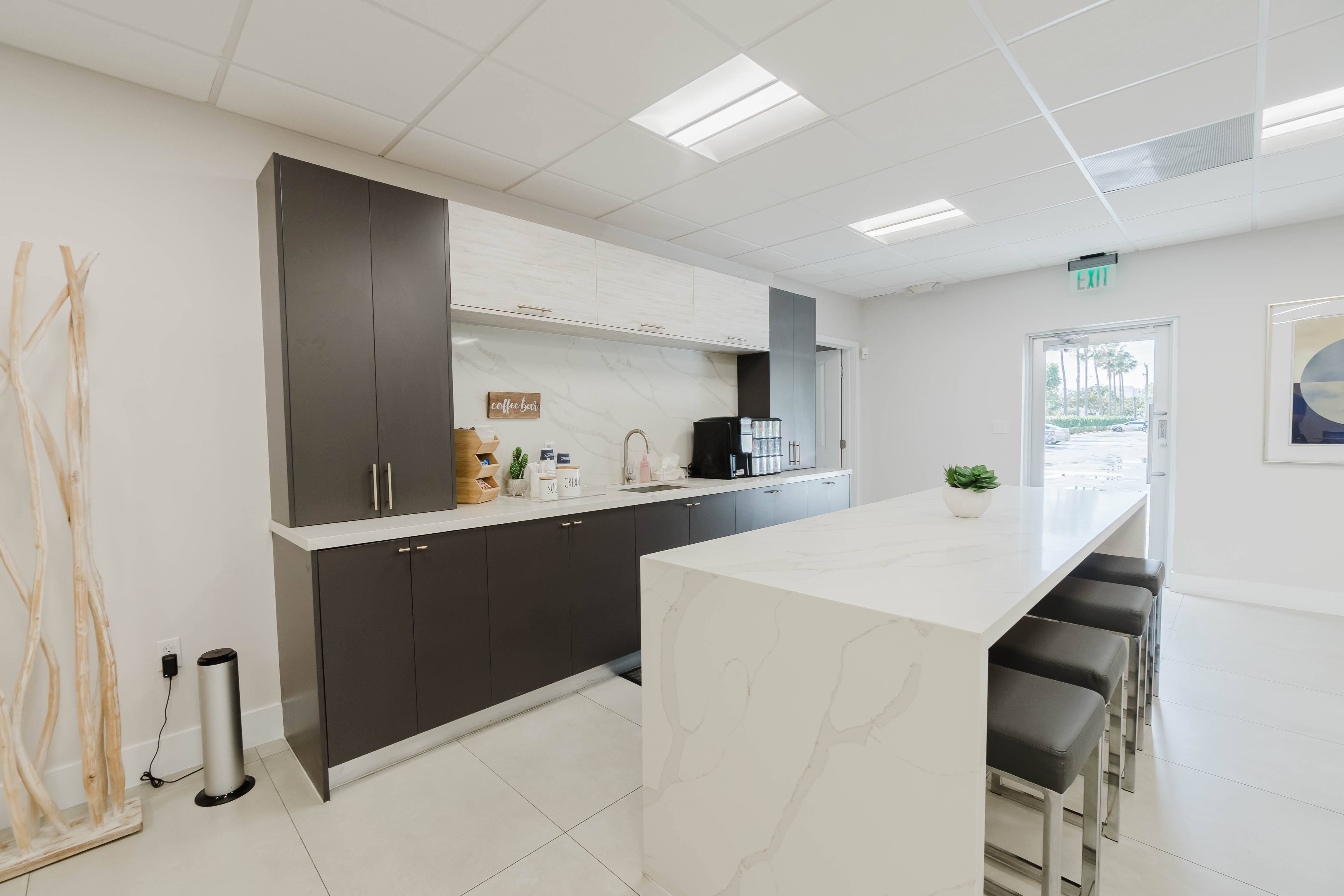 A kitchen with white countertops and black bar stools.