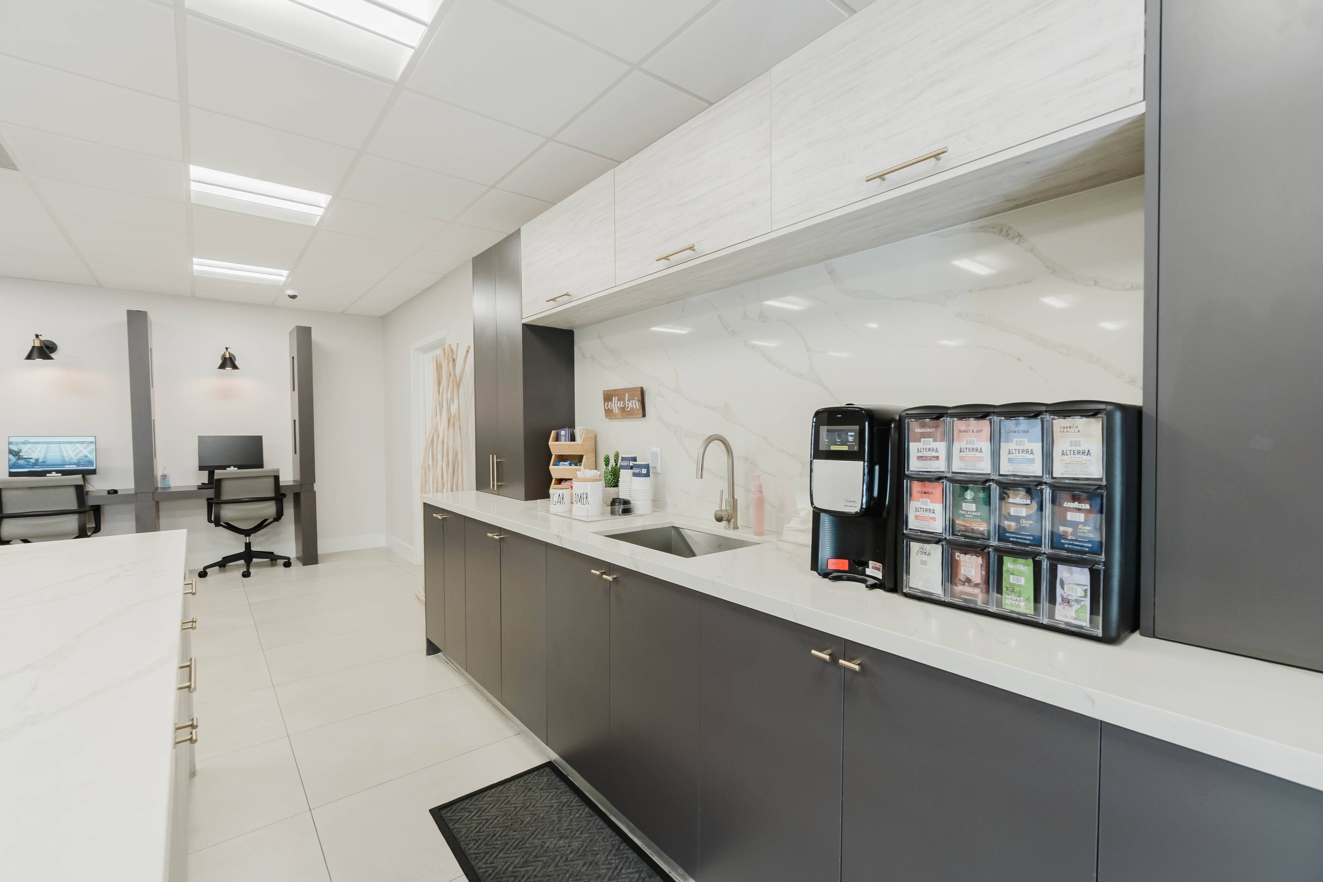 A modern kitchen with a white counter and a black fridge.