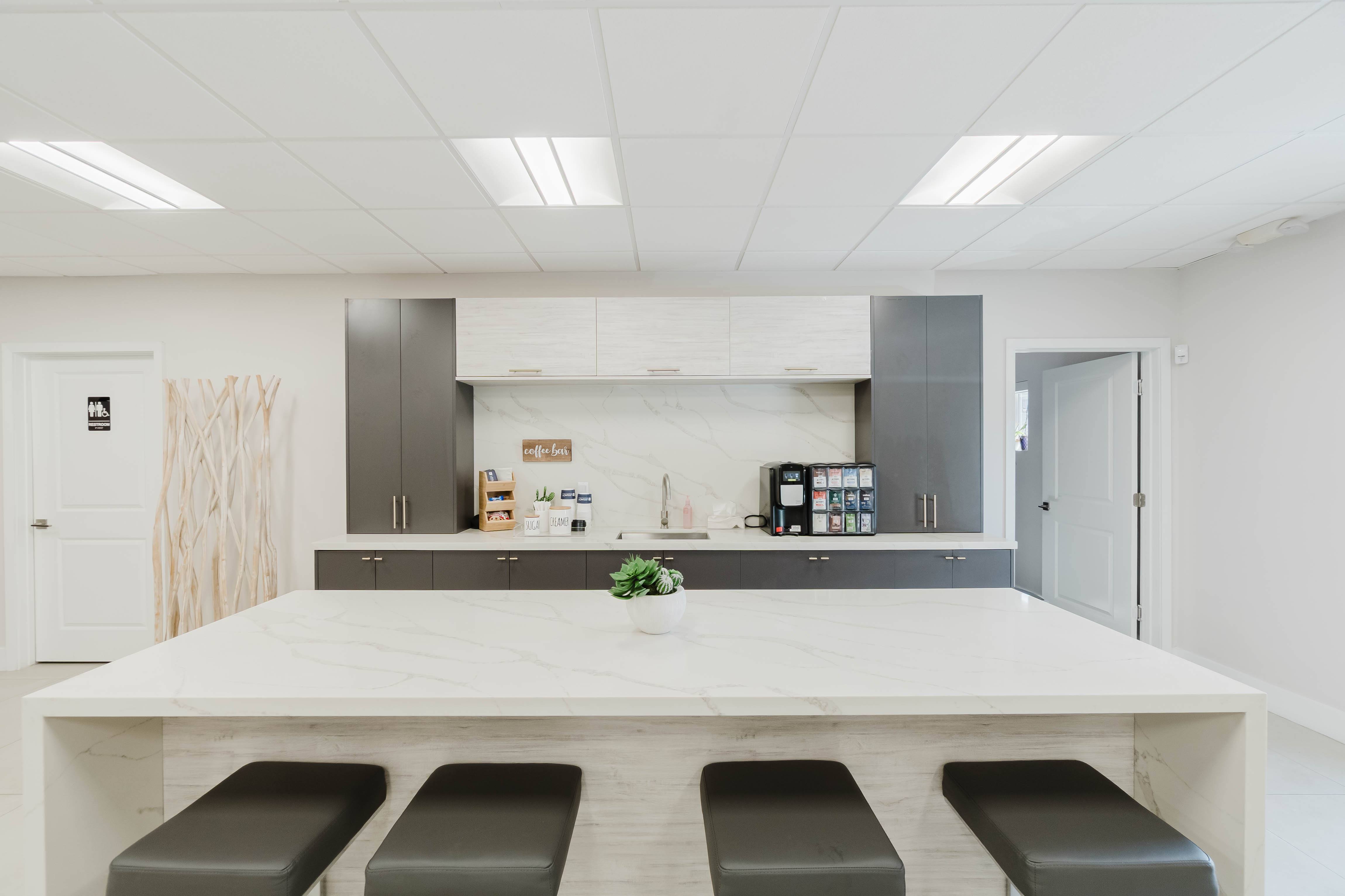 A modern kitchen with a white countertop and grey stools.