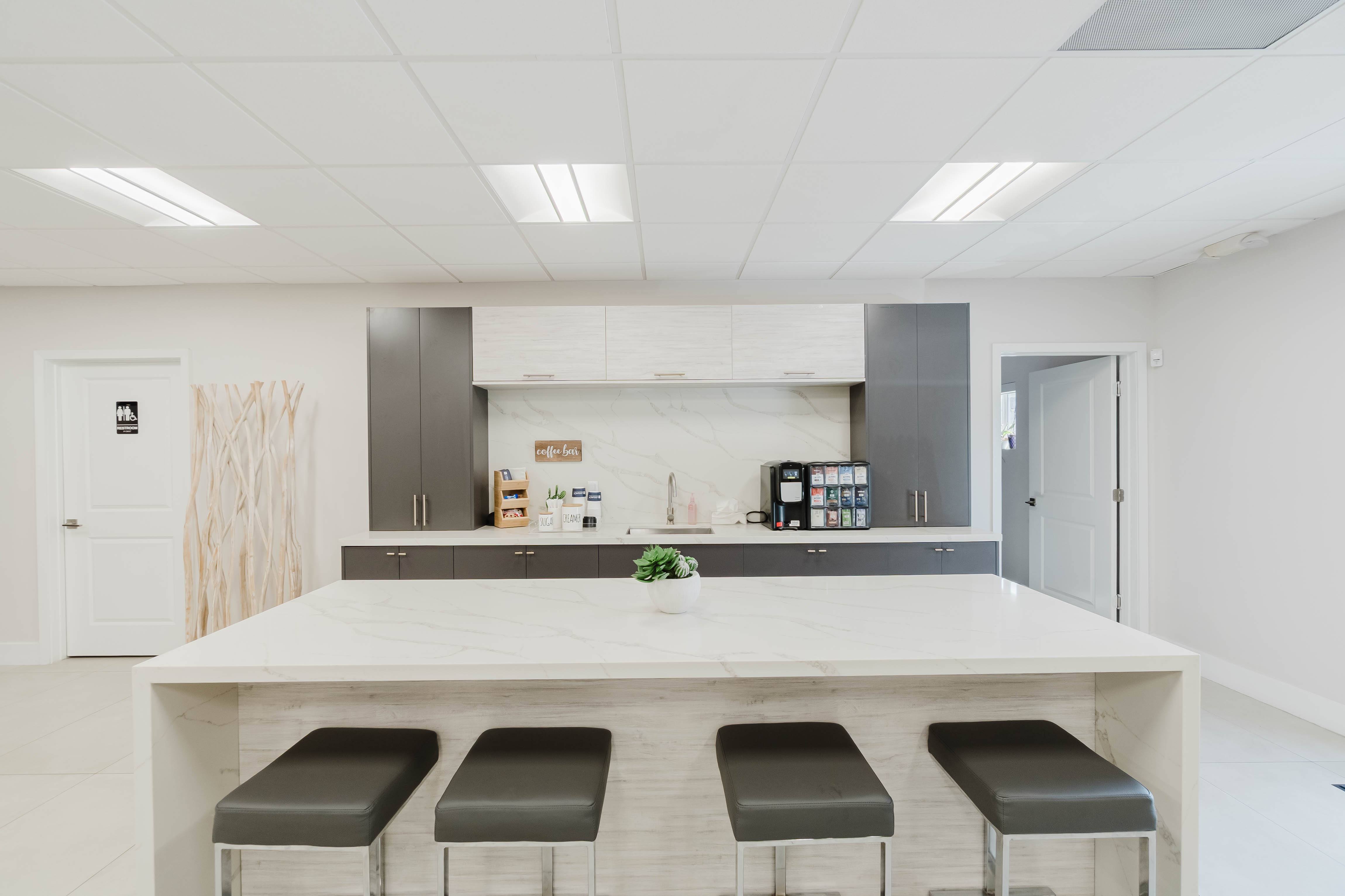 A kitchen with a white island and bar stools.