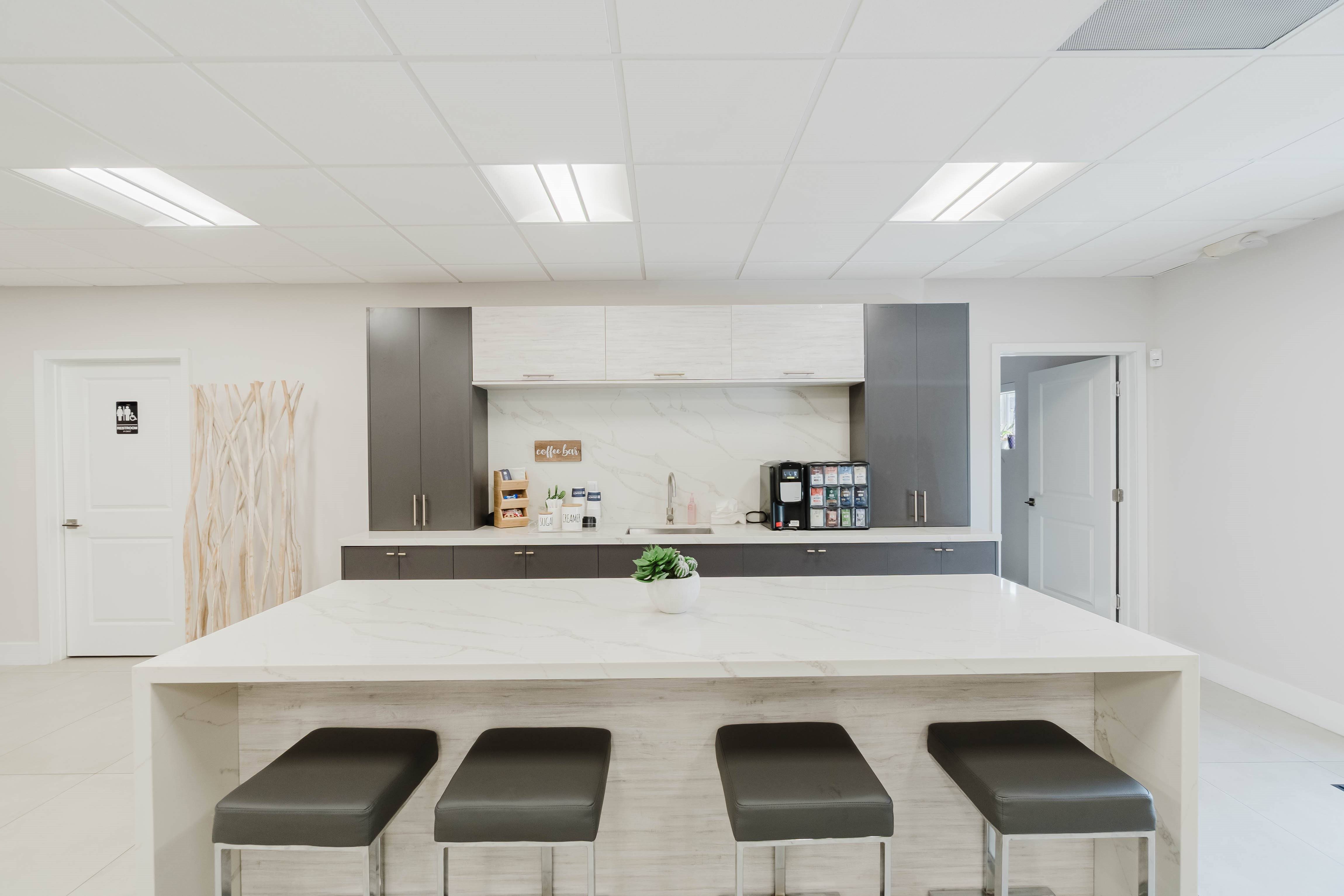 A kitchen with a white island and bar stools.