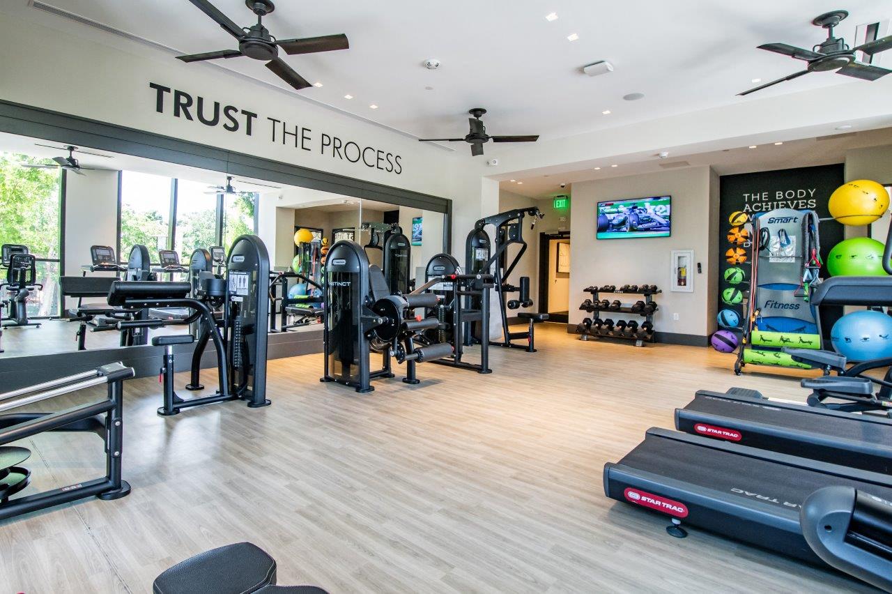 a gym with weights and cardio equipment and a sign saying trust the process