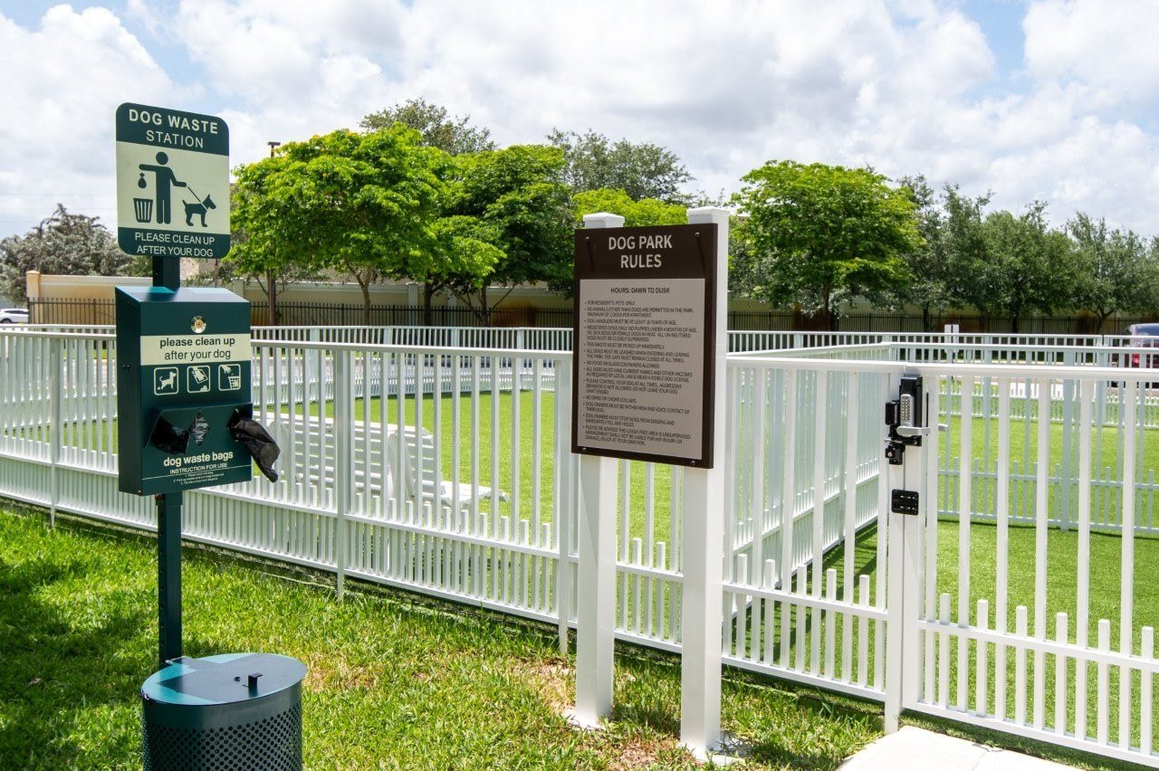 A signpost for a dog waste station is next to a fence.