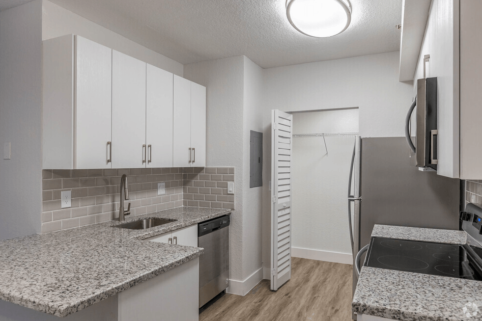 a kitchen with granite counter tops and a stainless steel refrigerator