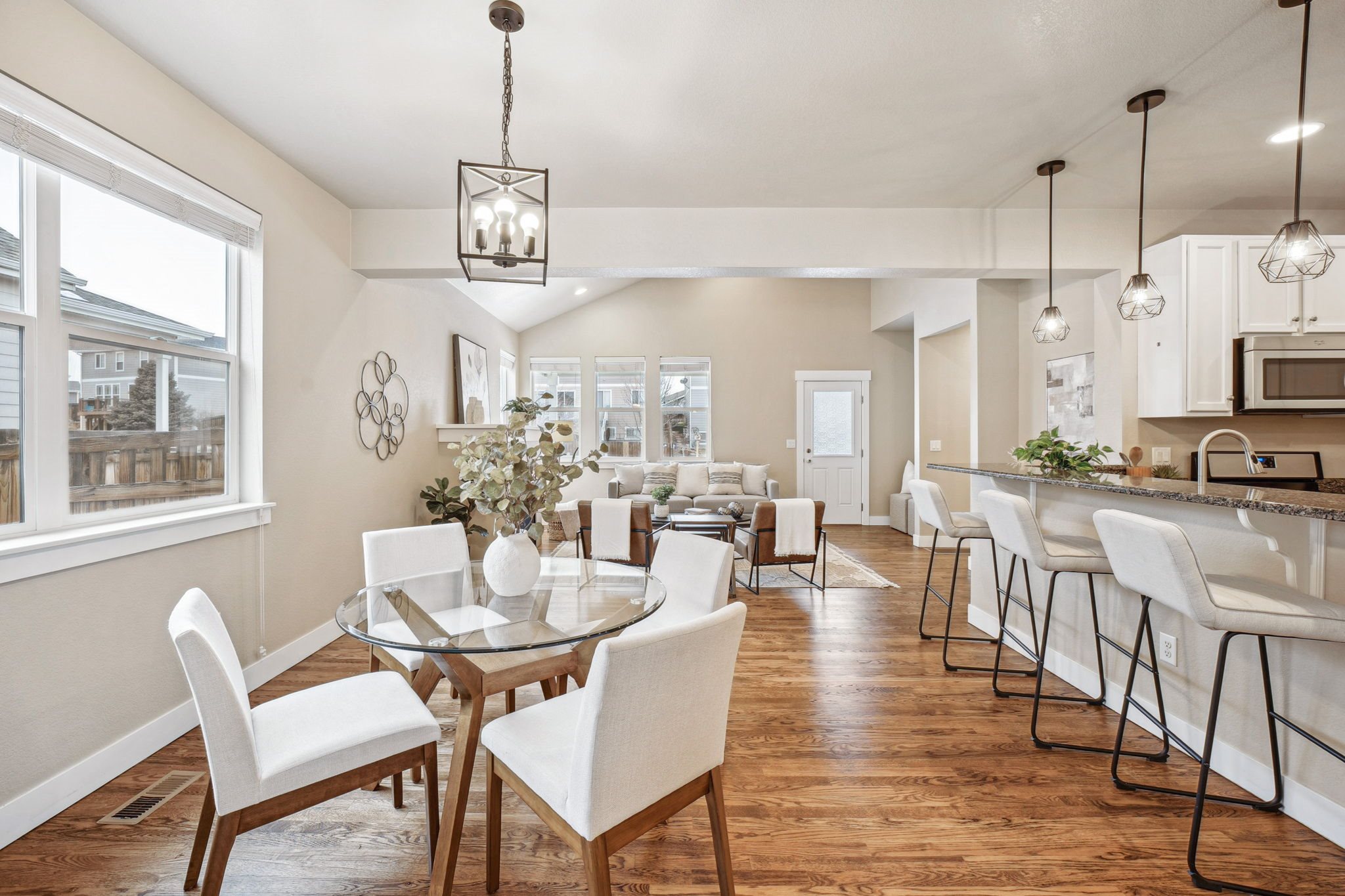 A dining room with a glass table and white chairs.