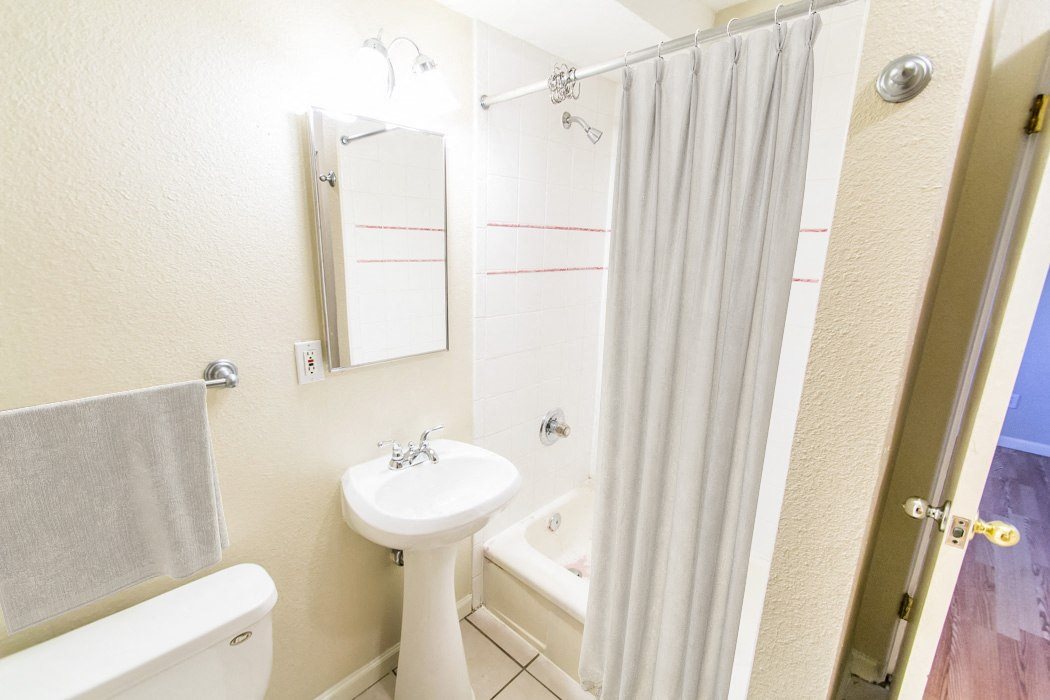 A white bathroom with a towel hanging on the wall.