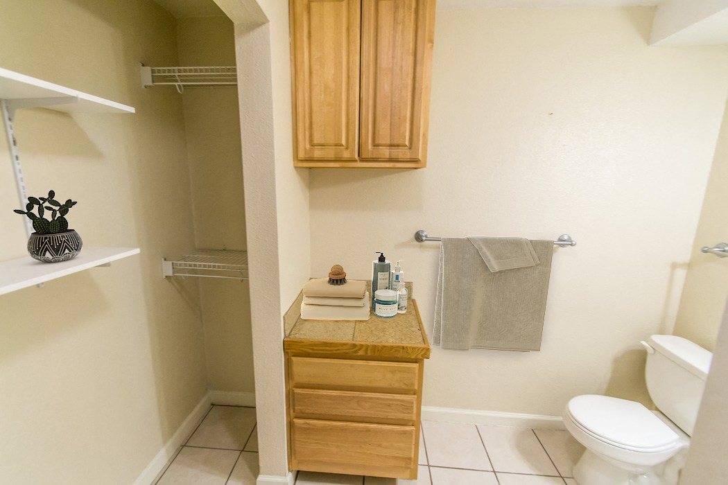A small bathroom with a toilet, sink, and wooden cabinets.