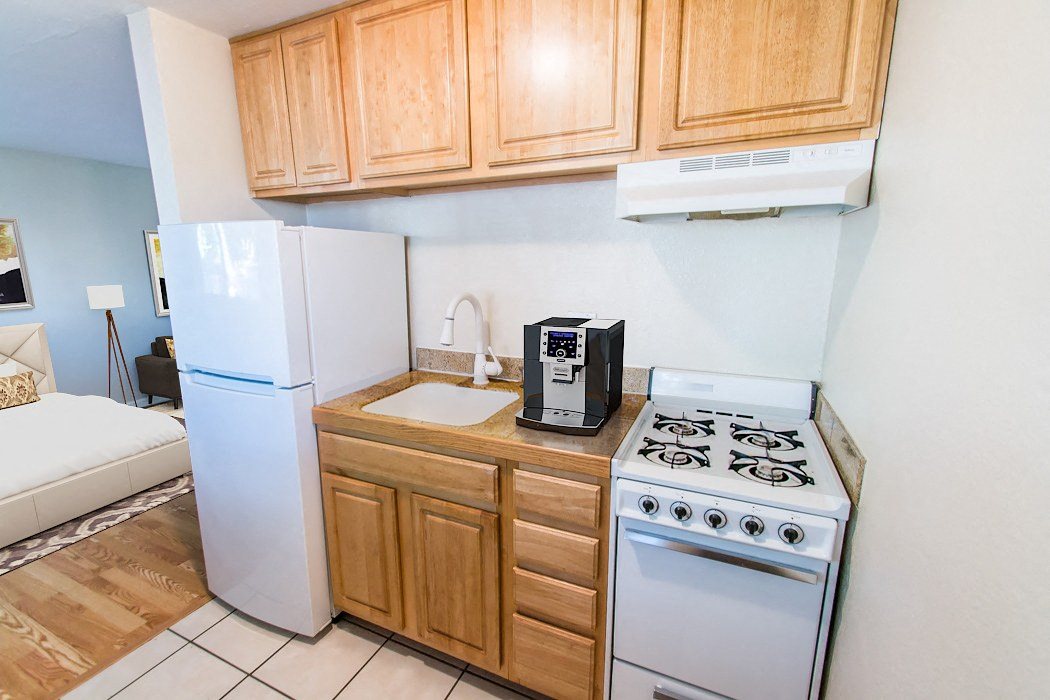 A kitchen with a white refrigerator, white stove, and wooden cabinets.