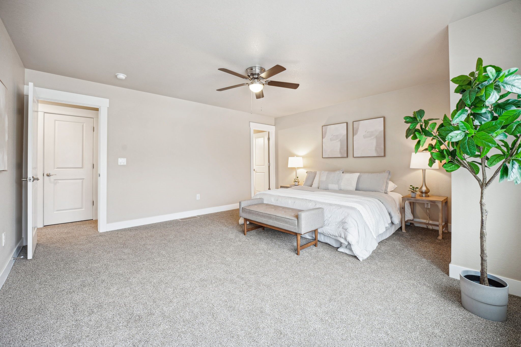 A bedroom with a bed, nightstand, and plant.