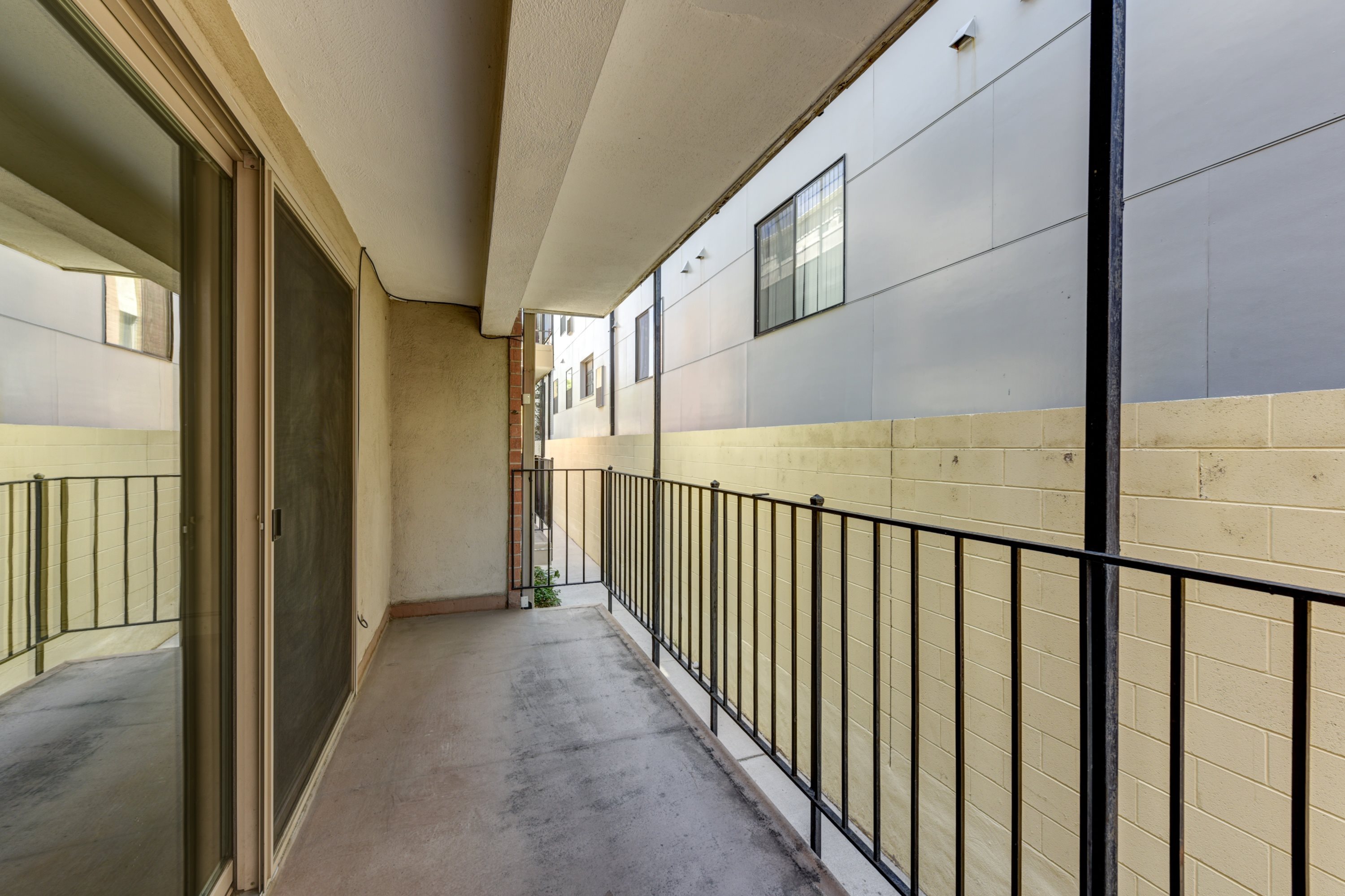 A long, narrow hallway with black railings and white walls.