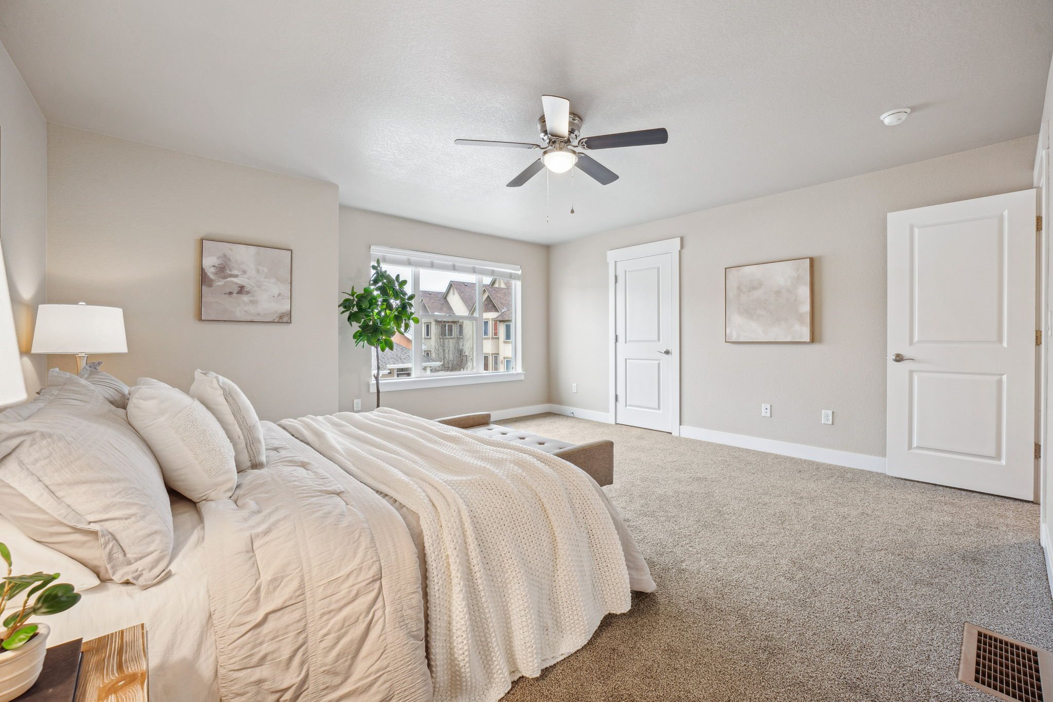 A bedroom with a large bed and a ceiling fan.