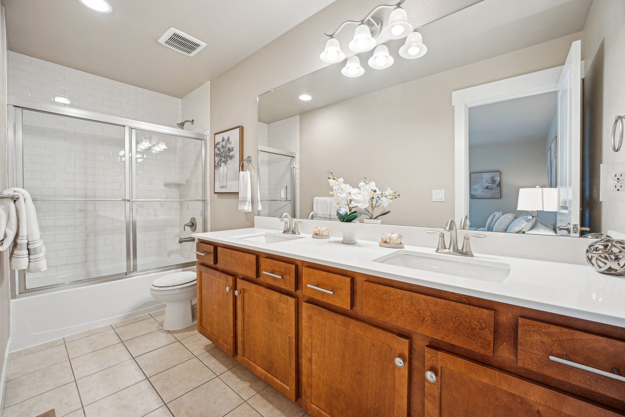 A bathroom with a white counter top and wooden cabinets.