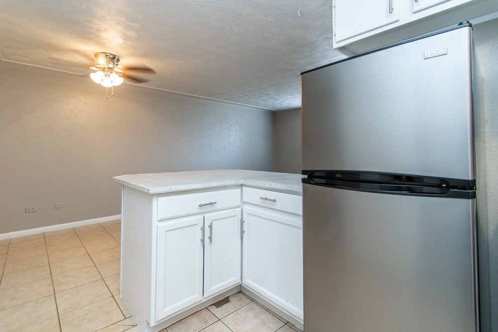 A kitchen with a white cabinet and a stainless steel refrigerator.