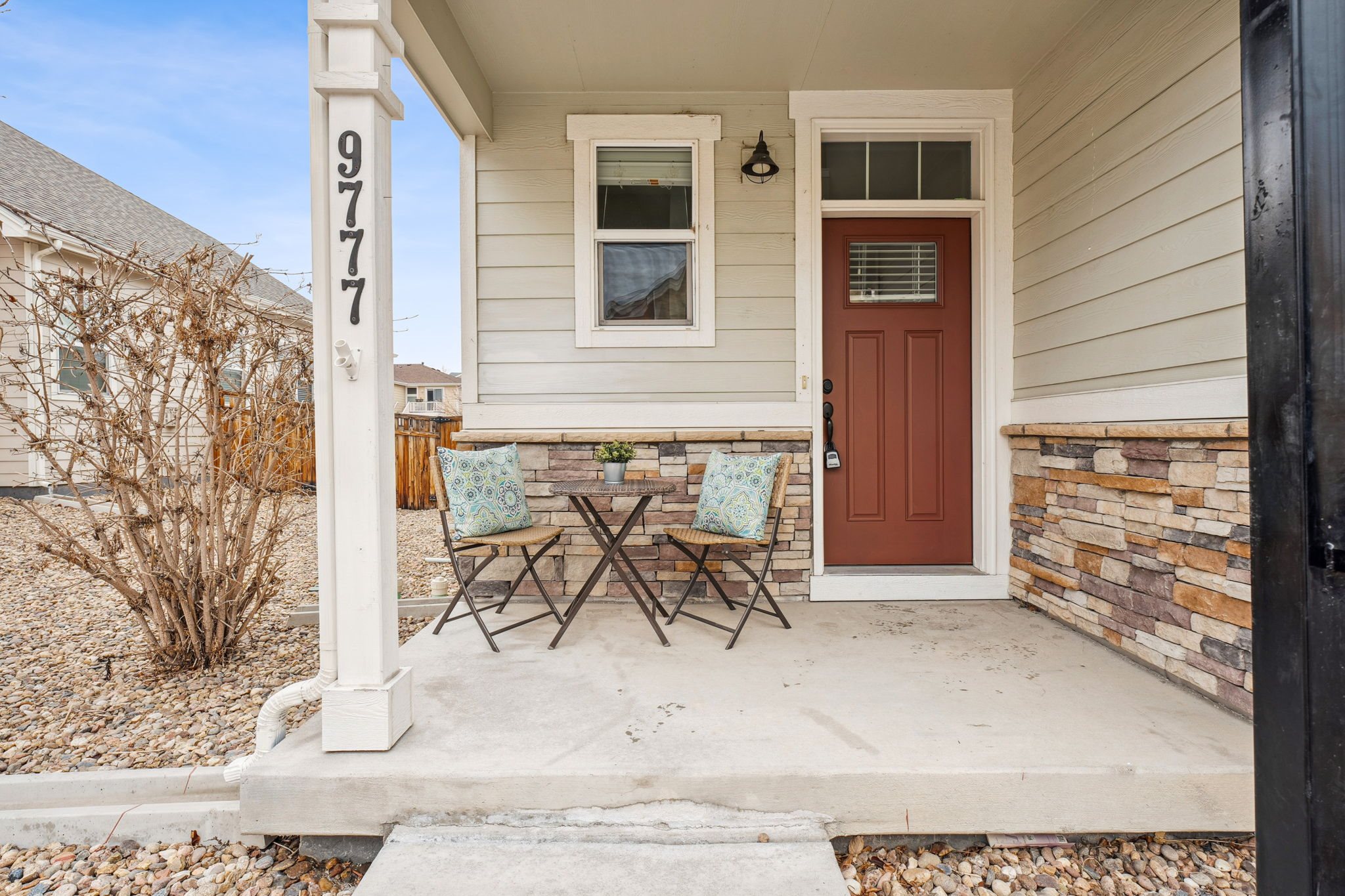 A house numbered 9777 has a brown door and a small porch.
