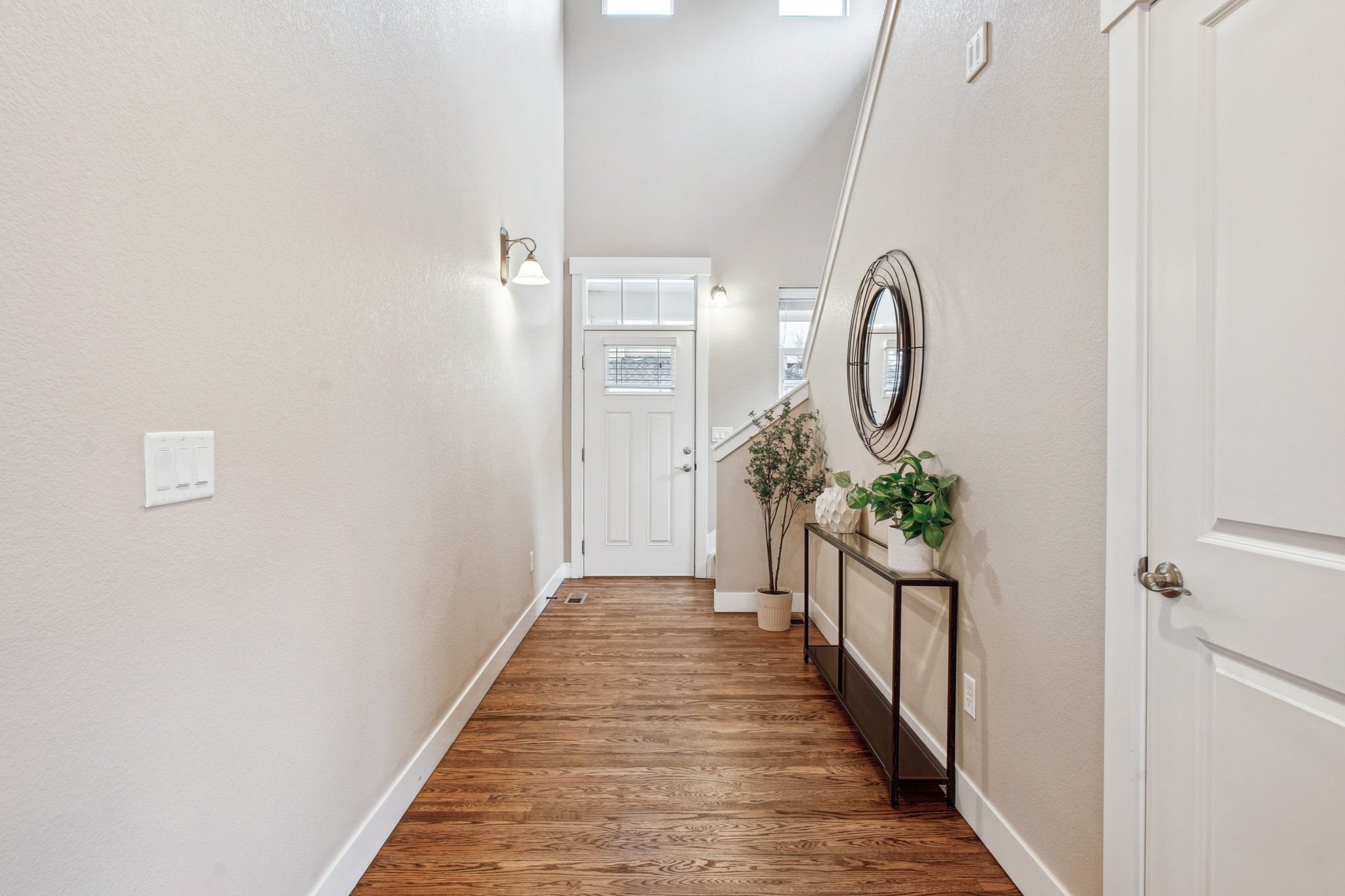 A hallway with a white door and a mirror on the wall.