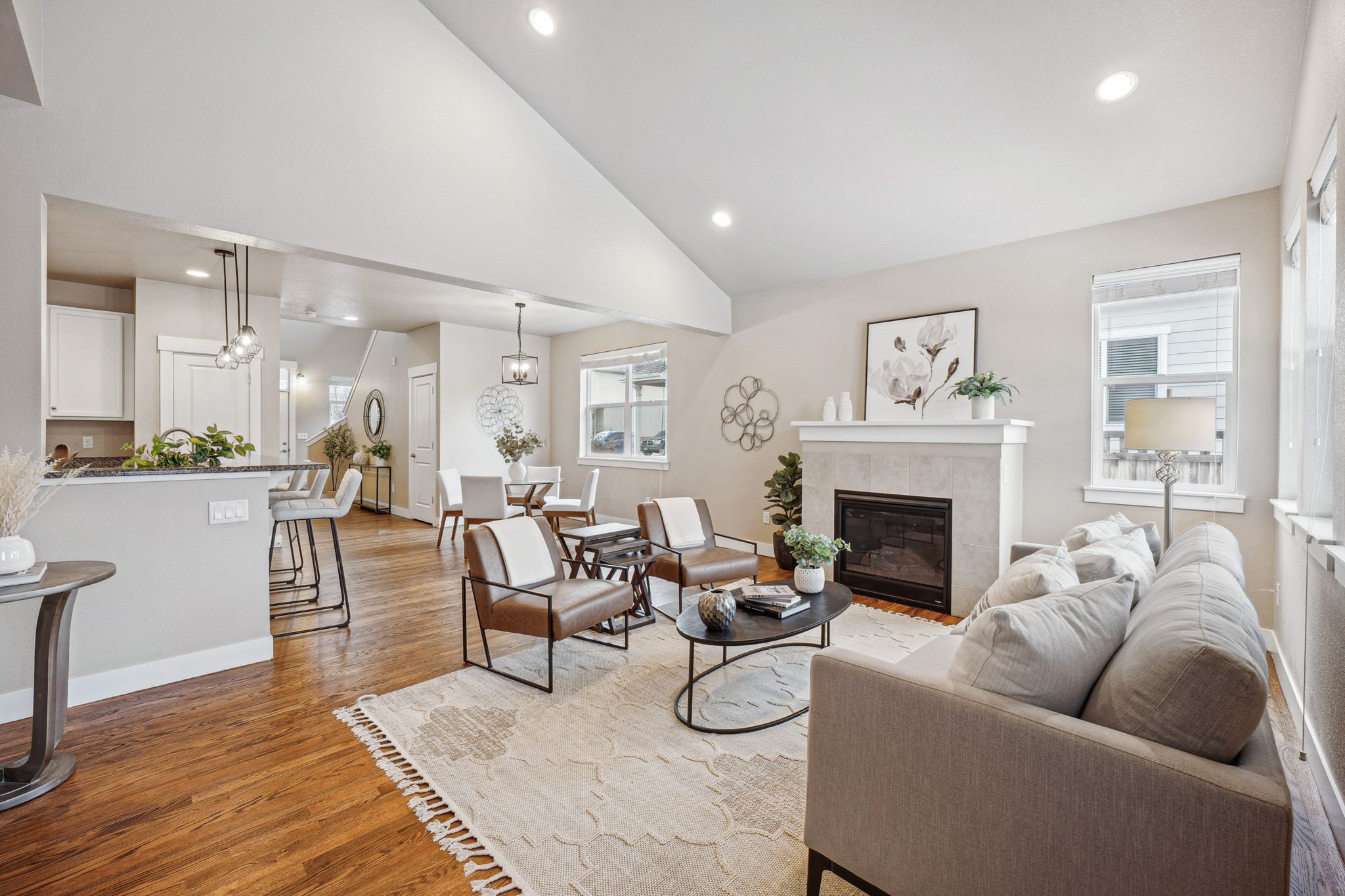 A modern living room with a fireplace and a dining area in the background.