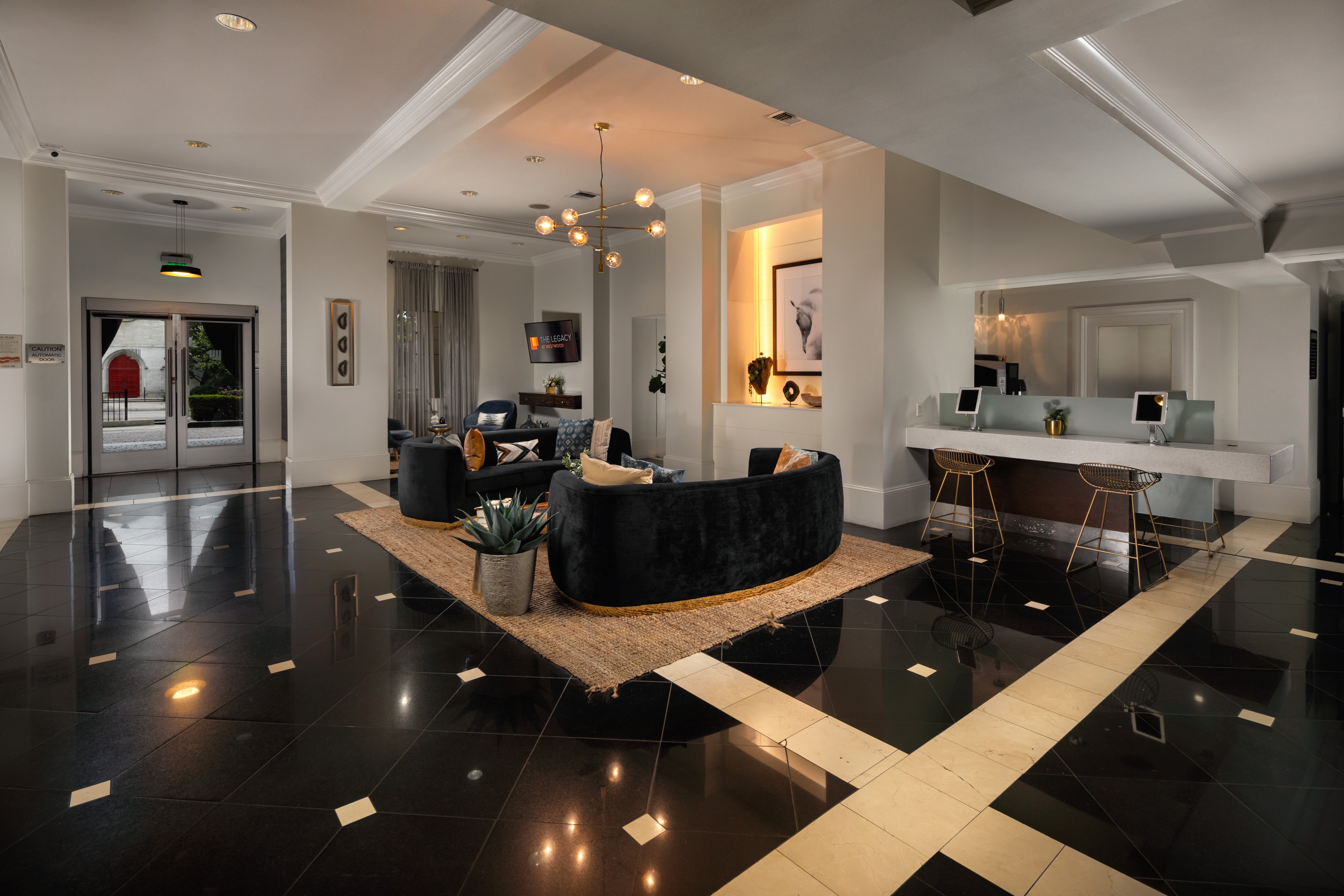 A black and white tiled floor with a round black couch in the middle.